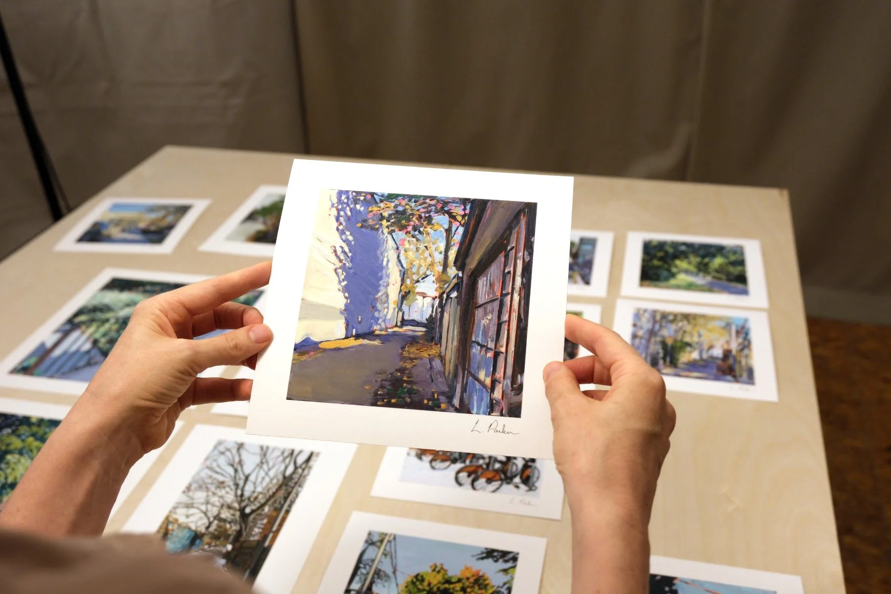 Leslie Parker holding a fine art print of a tree shadow on a Leslieville laneway wall