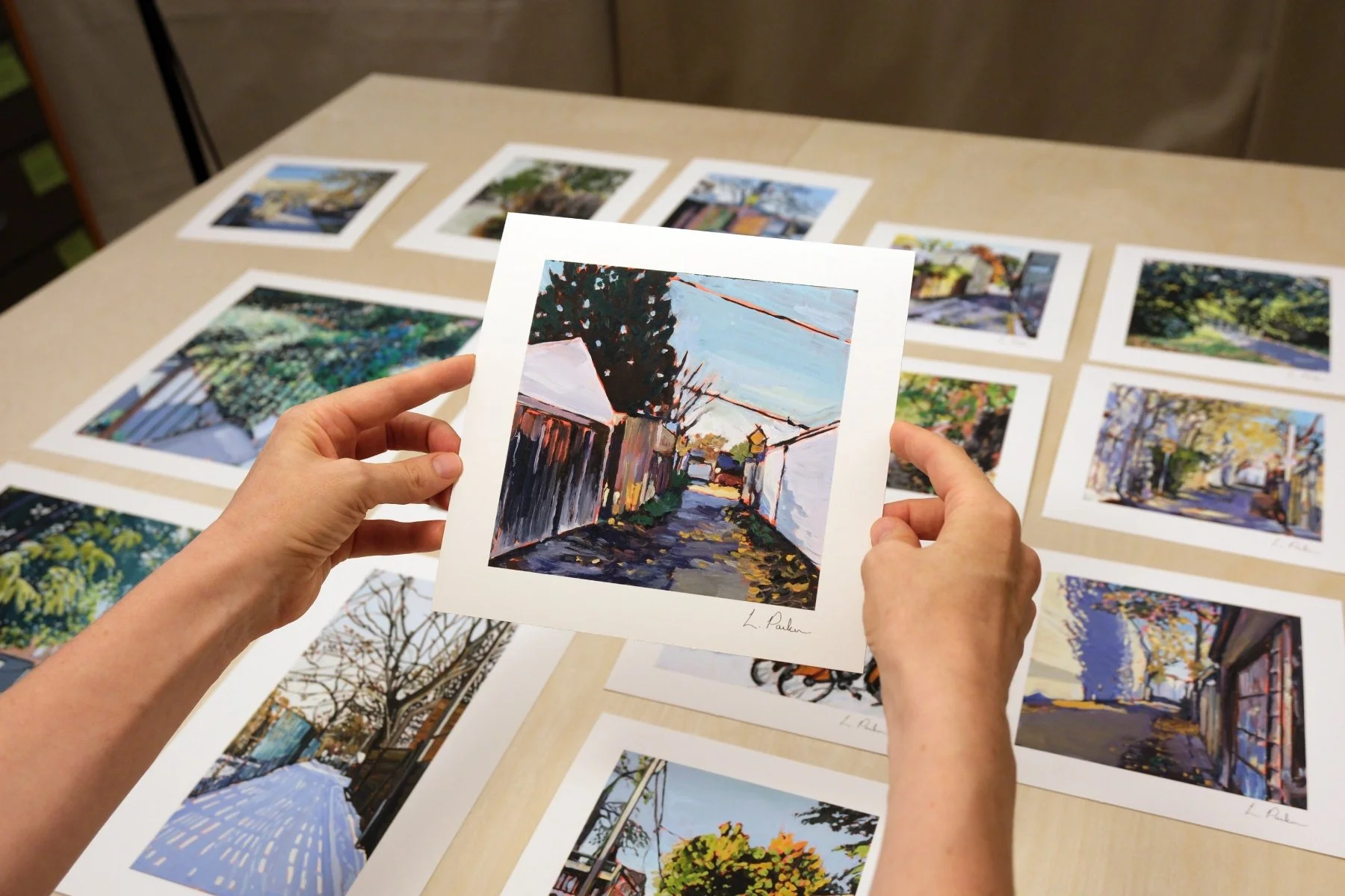 Leslie Parker holding a fine art print of a Leslieville laneway in fall