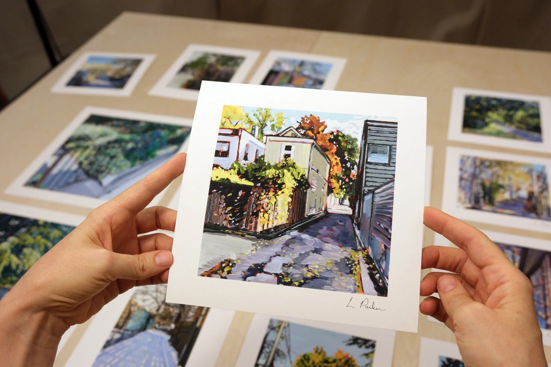 Leslie Parker holding a fine art print of sunlight on a Leslieville fence