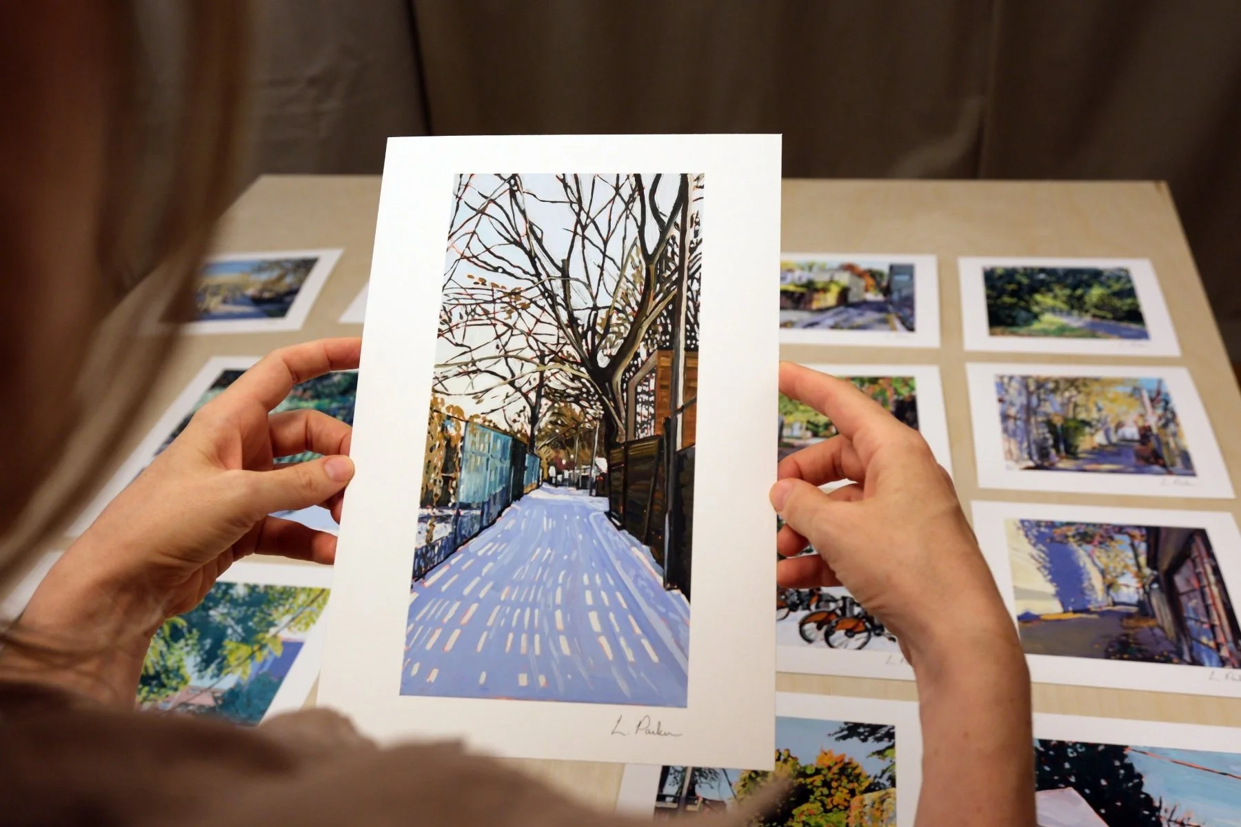 Leslie Parker holding a fine art print of a fence shadow across the snow