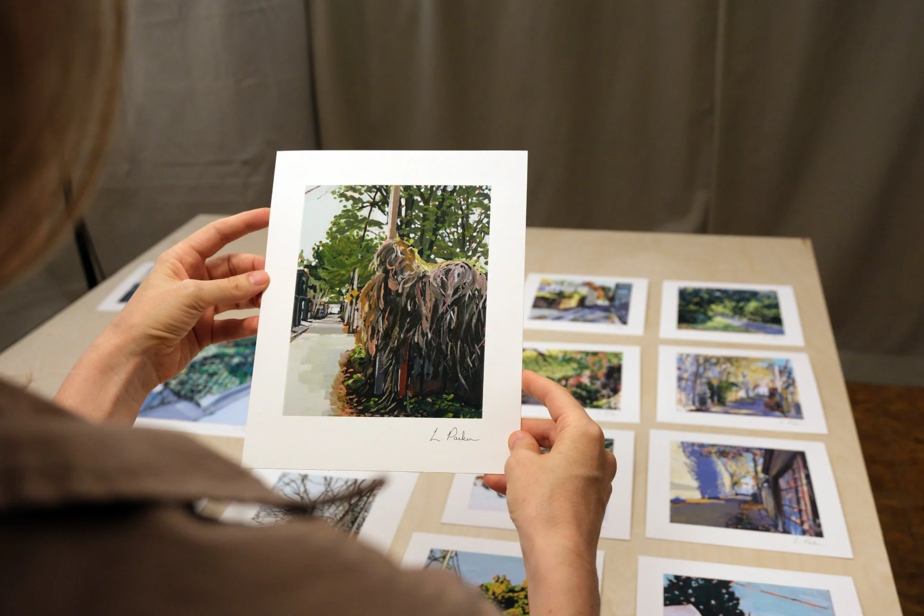 Leslie Parker holding a fine art print of a vine-covered Toronto laneway fence