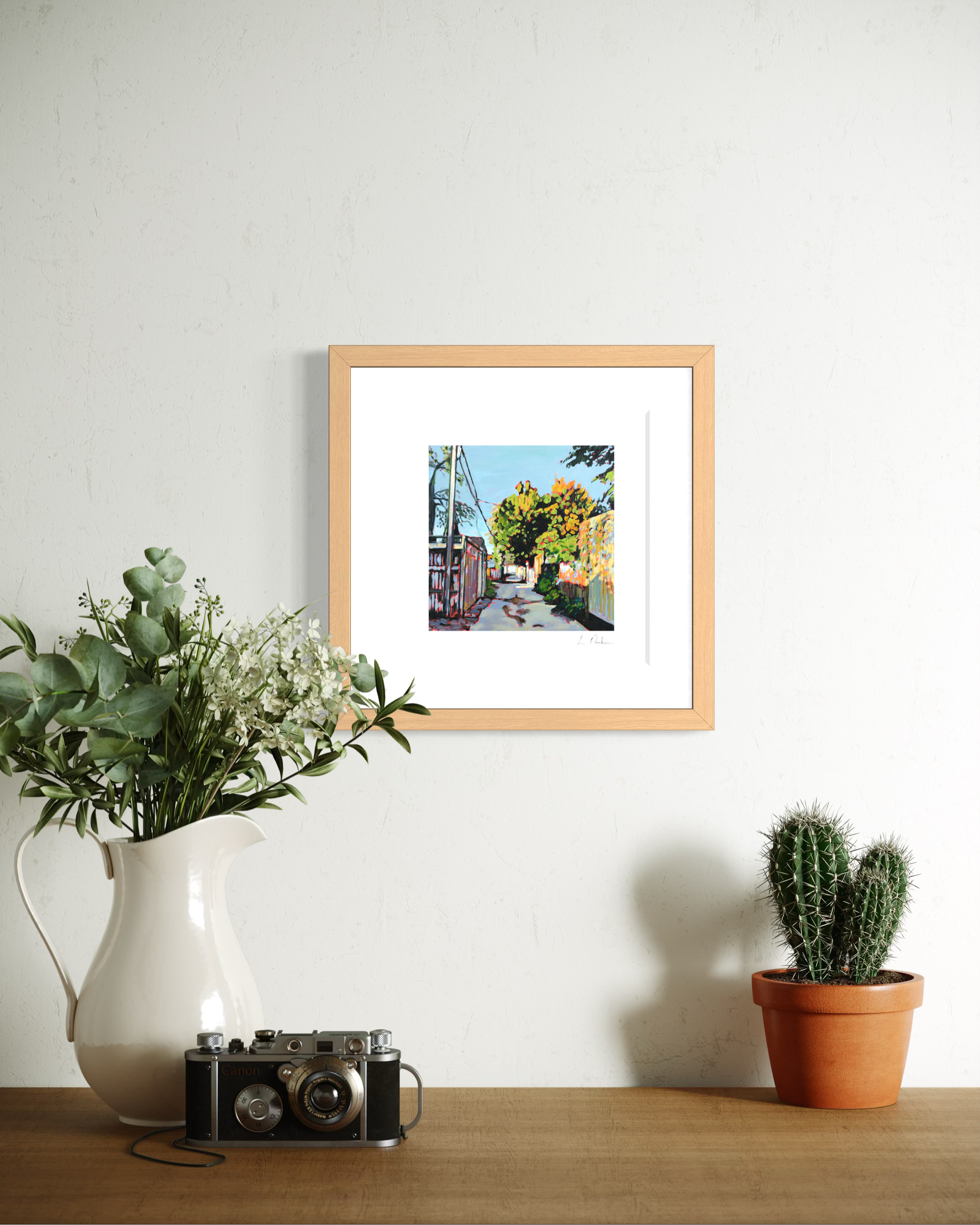 a grey Leslieville laneway in winter — framed Toronto art print hanging on a wall above a mantle with plants