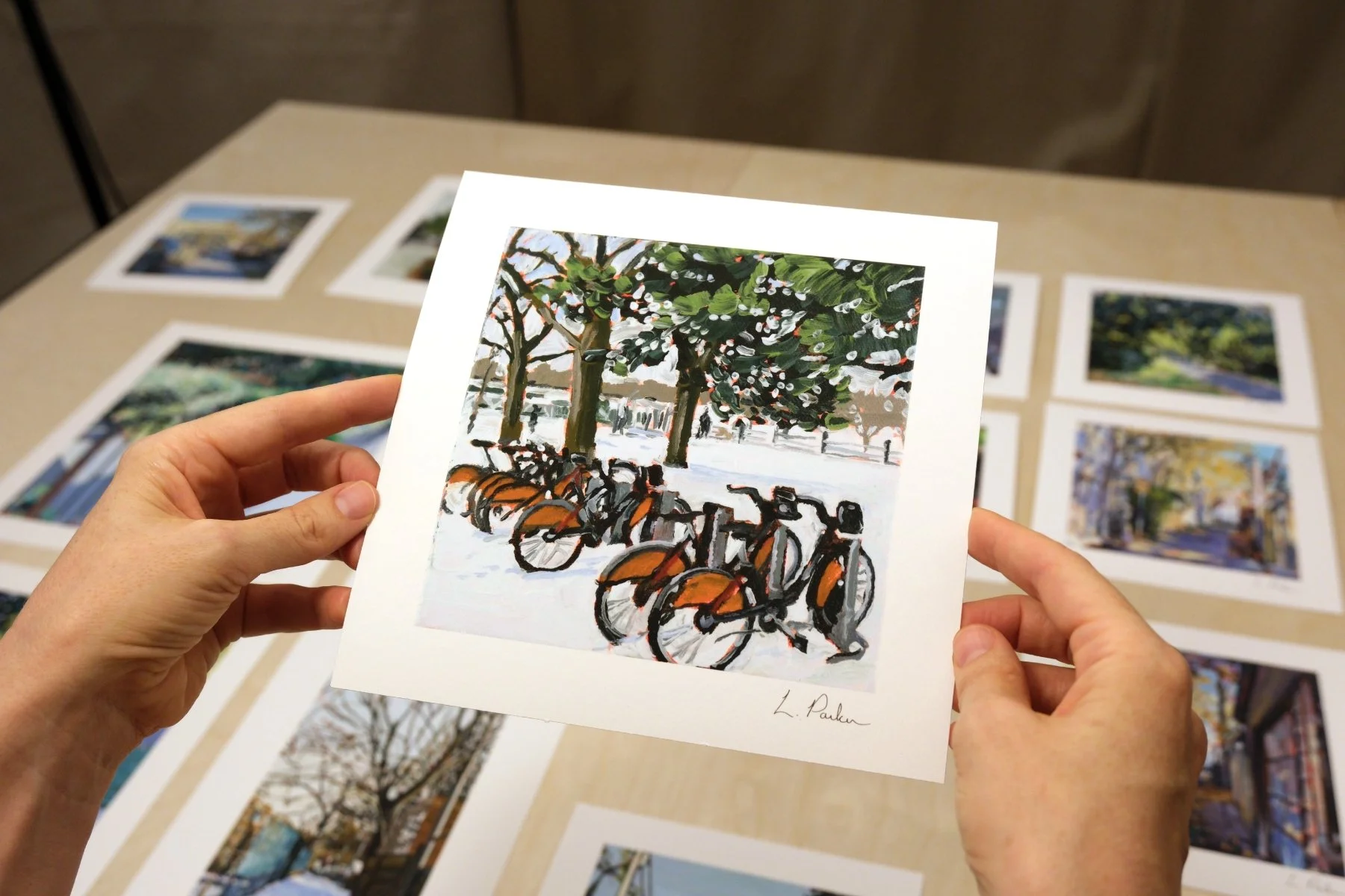Leslie Parker holding a fine art print of bike-share bikes in the snow at Greenwood Park