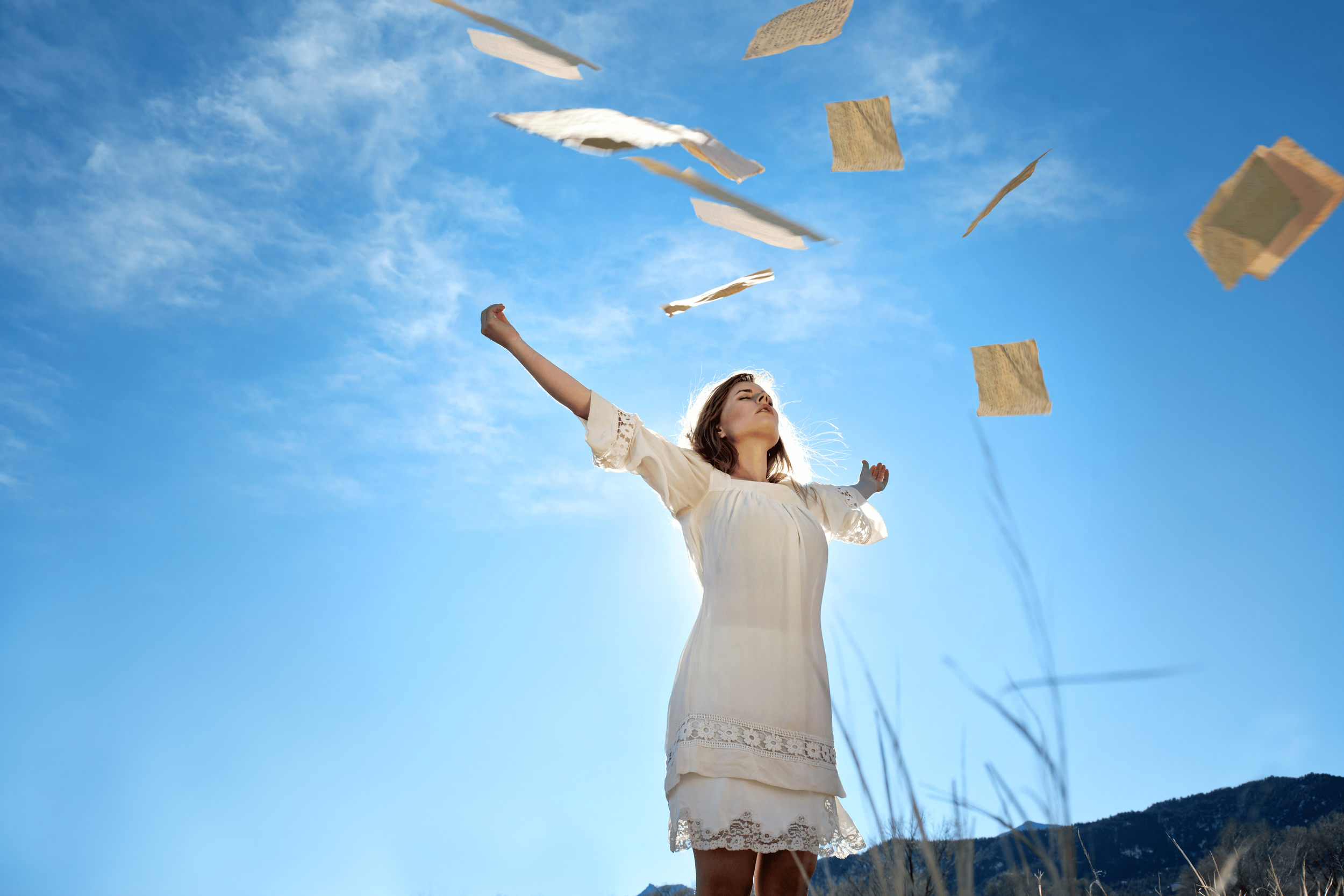 woman releasing papers into the wind to symbolize letting go