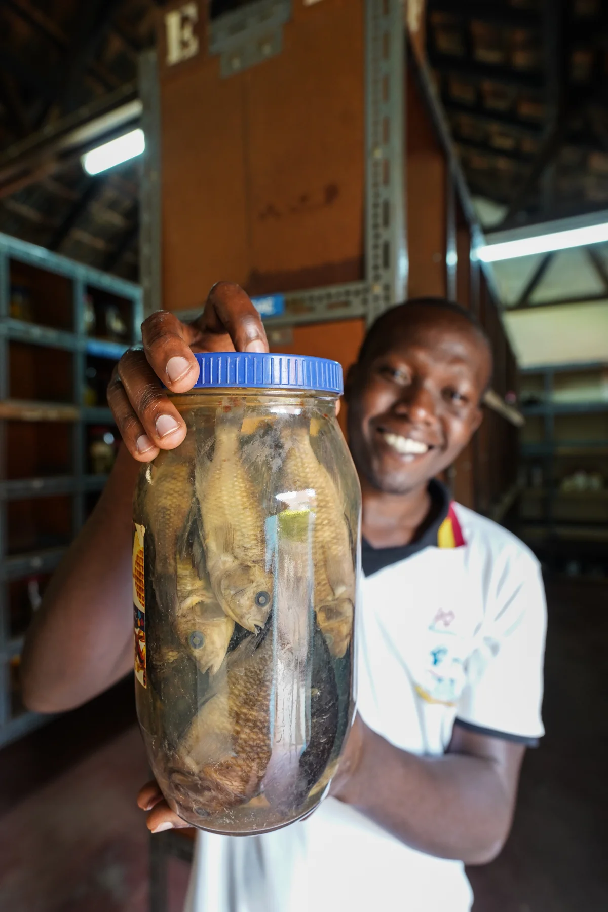 Lugya Jessy, a research assistant at NaFIRRI, holds up a jar containing one of the many haplochromine cichlid species that went extinct after the introduction of the Nile perch