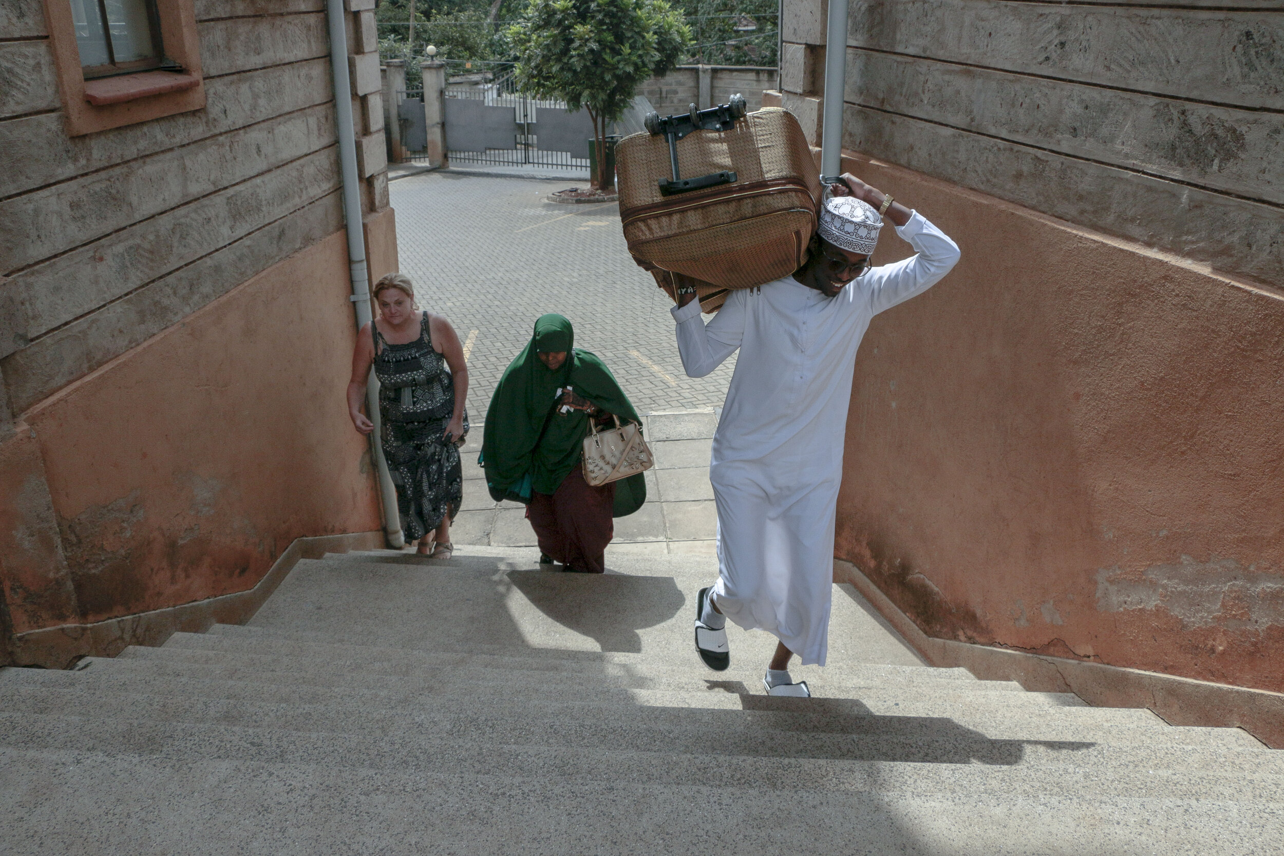  Khalid Ahmed, Kosar's cousin, helps lift a suitcase up the steps while Hamdi Kosar and Jessica Rohloff follow Aug. 23, 2019 in Nairobi. Kosar had met Ahmed just several days before and has many family members that she has never met after being reset