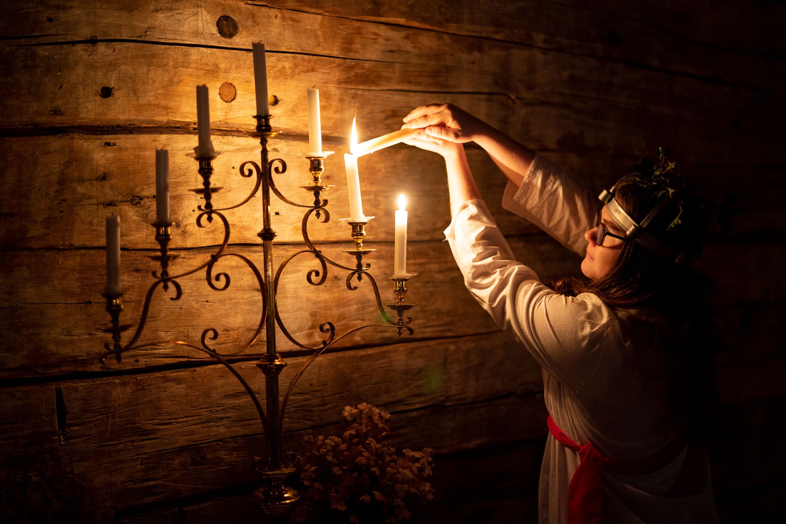  Becka Newcomb, 16, lights a candle in the old church at the Gammelgården Museum for the Saint Lucia Day celebration Dec. 11, 2022 in Scandia, Minn. Every year, a high school girl is picked to play Saint Lucia to honor the Swedish tradition of bringi