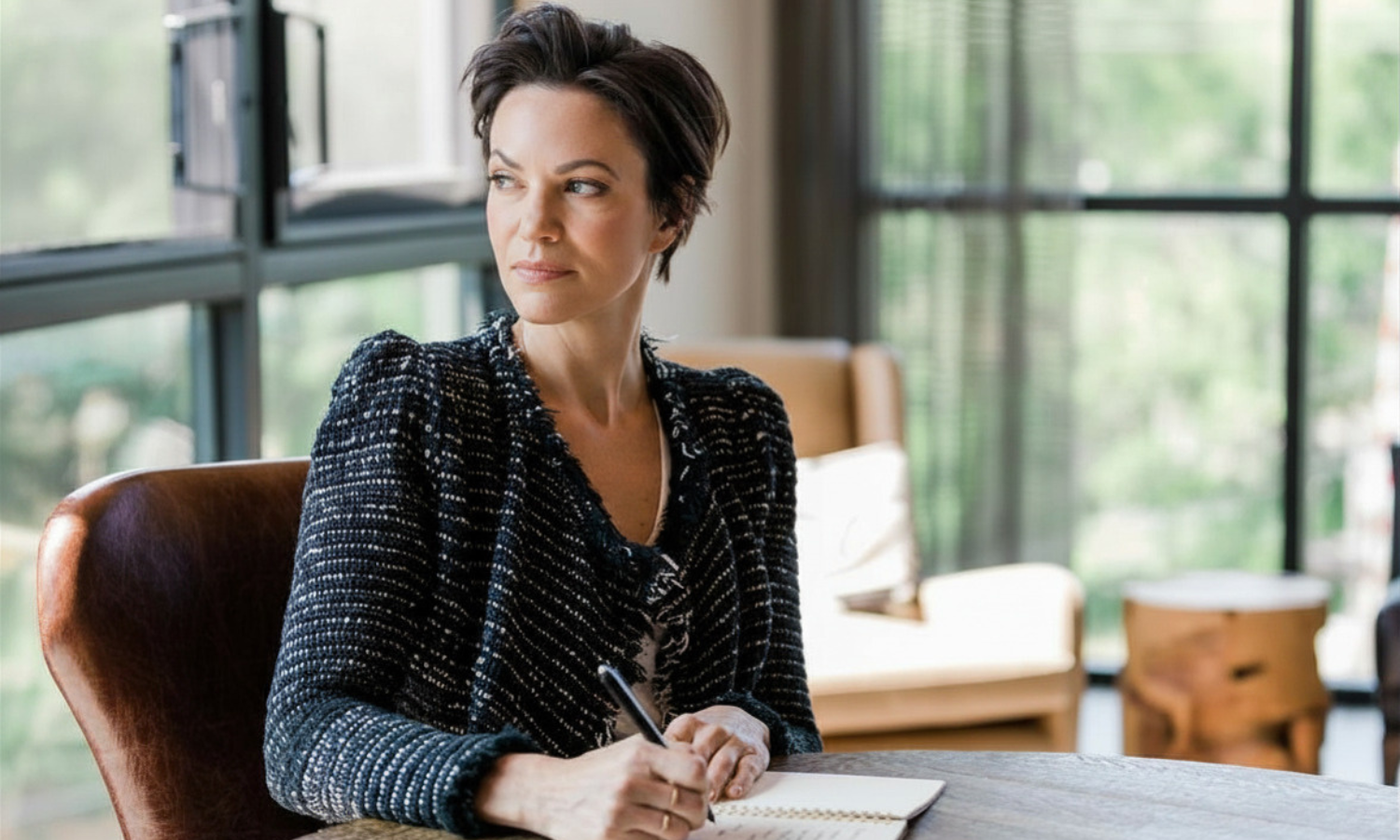 Heather Rees - woman looking over her shoulder while sitting at a desk with a notebook