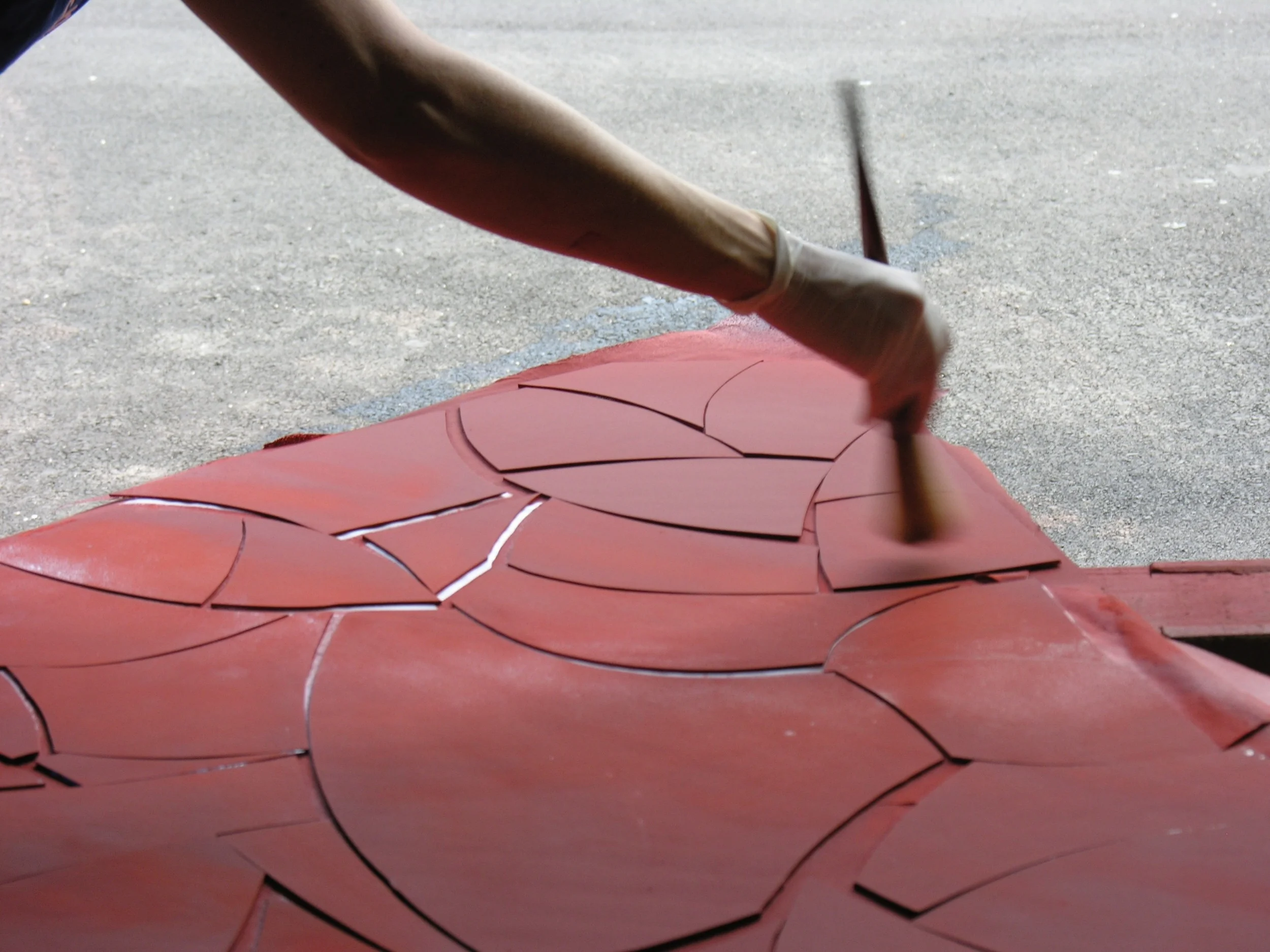This is the silver stain being applied to the blue glass. The silver stain itself is actually clear, but we add the red "terracotta" so that we can see where wer are applying it to give consistent results. The glass is then placed in the fire and the terracotta wiped off. Leaving the glass now looking more blueish green and yellow. 