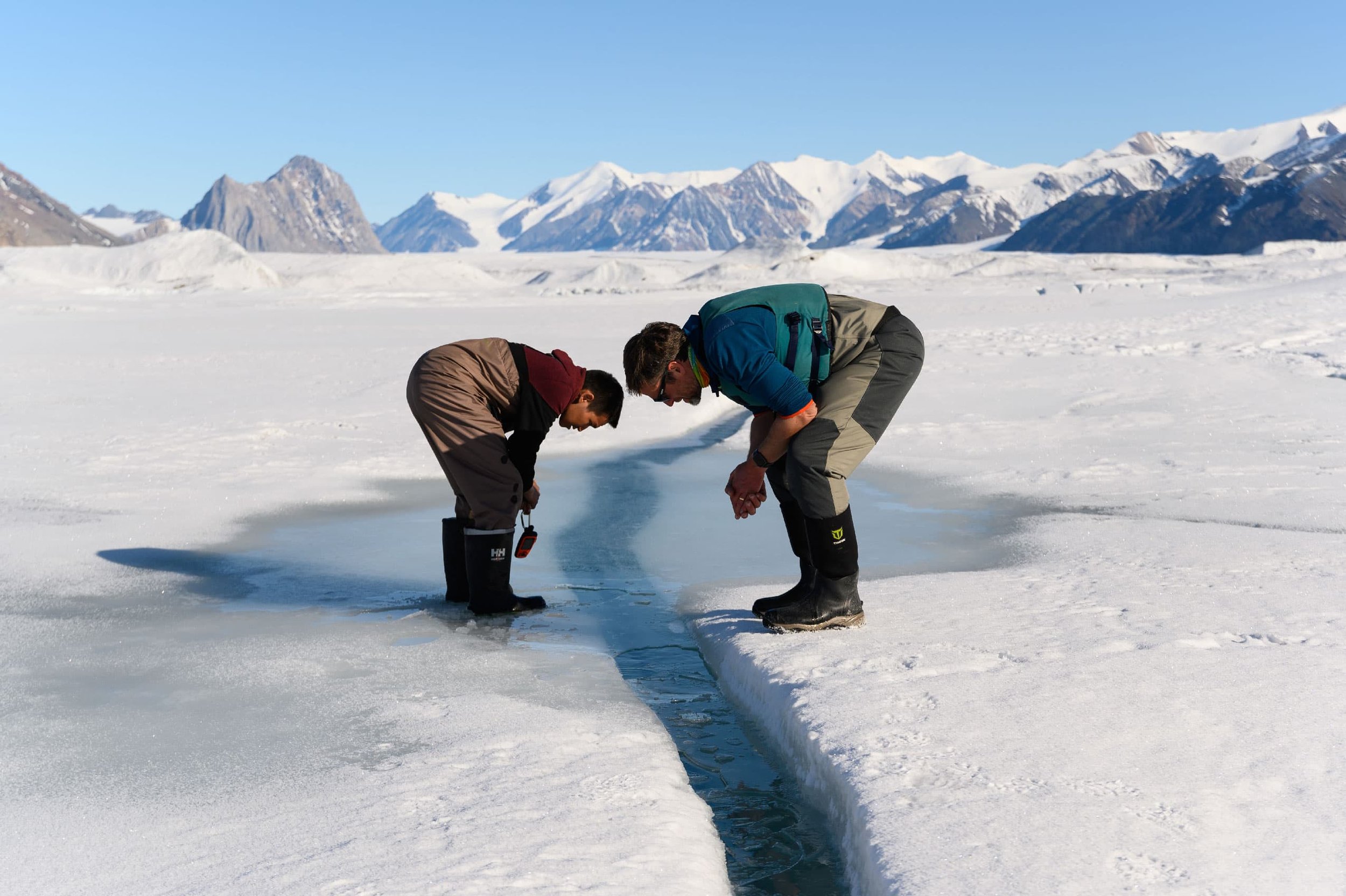  Joseph Shoapik, a resident of Grise Fiord, Nvt., peers down into a crack in the ice alongside Alex Forrest, a limnologist from the University of California, Davis. Just below this ice, a thin layer of freshwater used to float on top of the seawater 