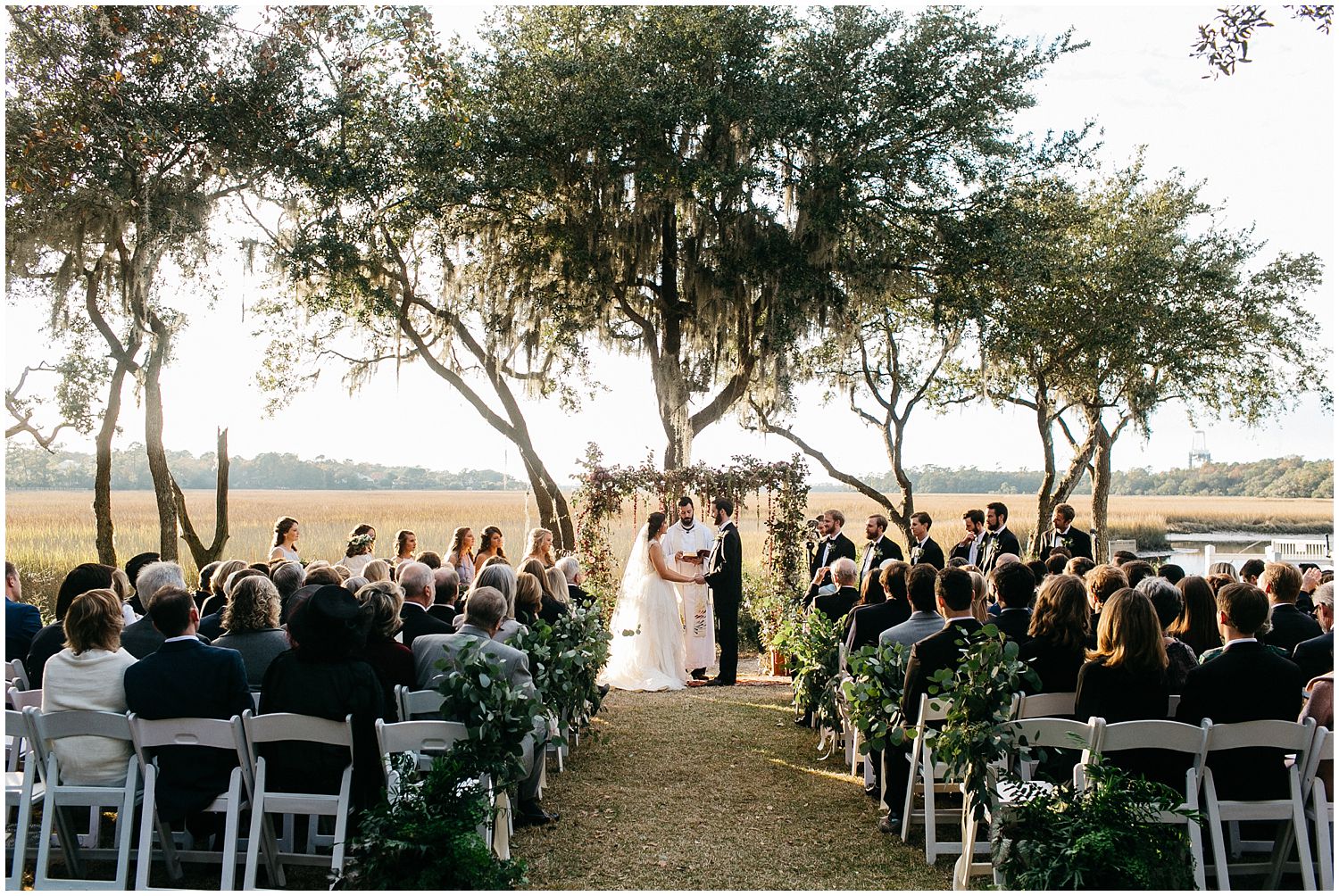 wedding ceremony on marsh with floral arbor