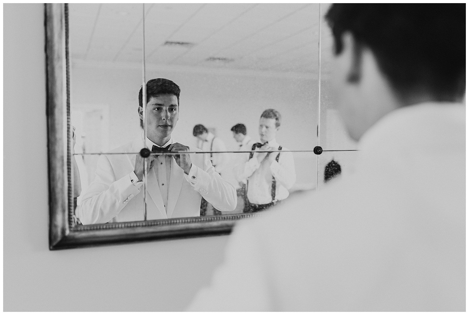 groom getting dressed in mirror