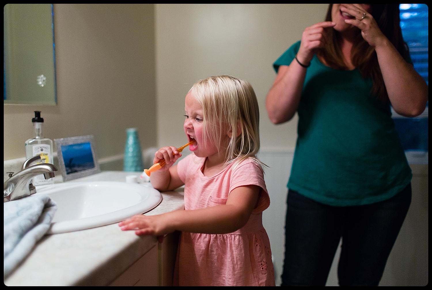 Mother teaches daughter how to brush her teeth.