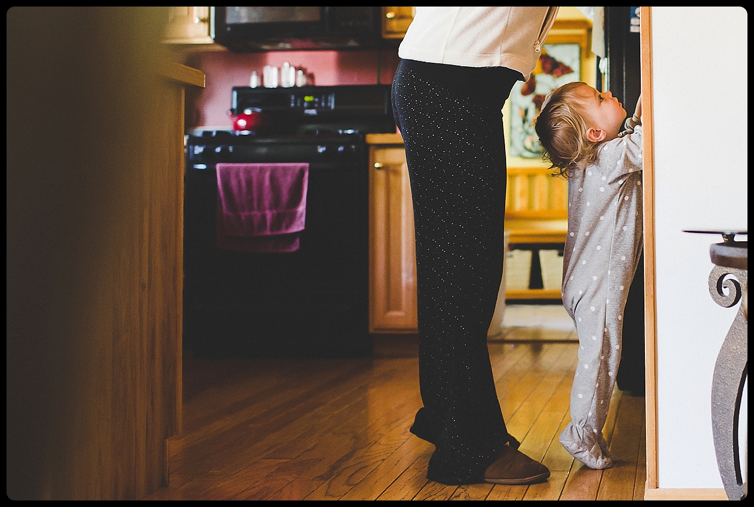 Little girl tries to reach table as mom stands over her.