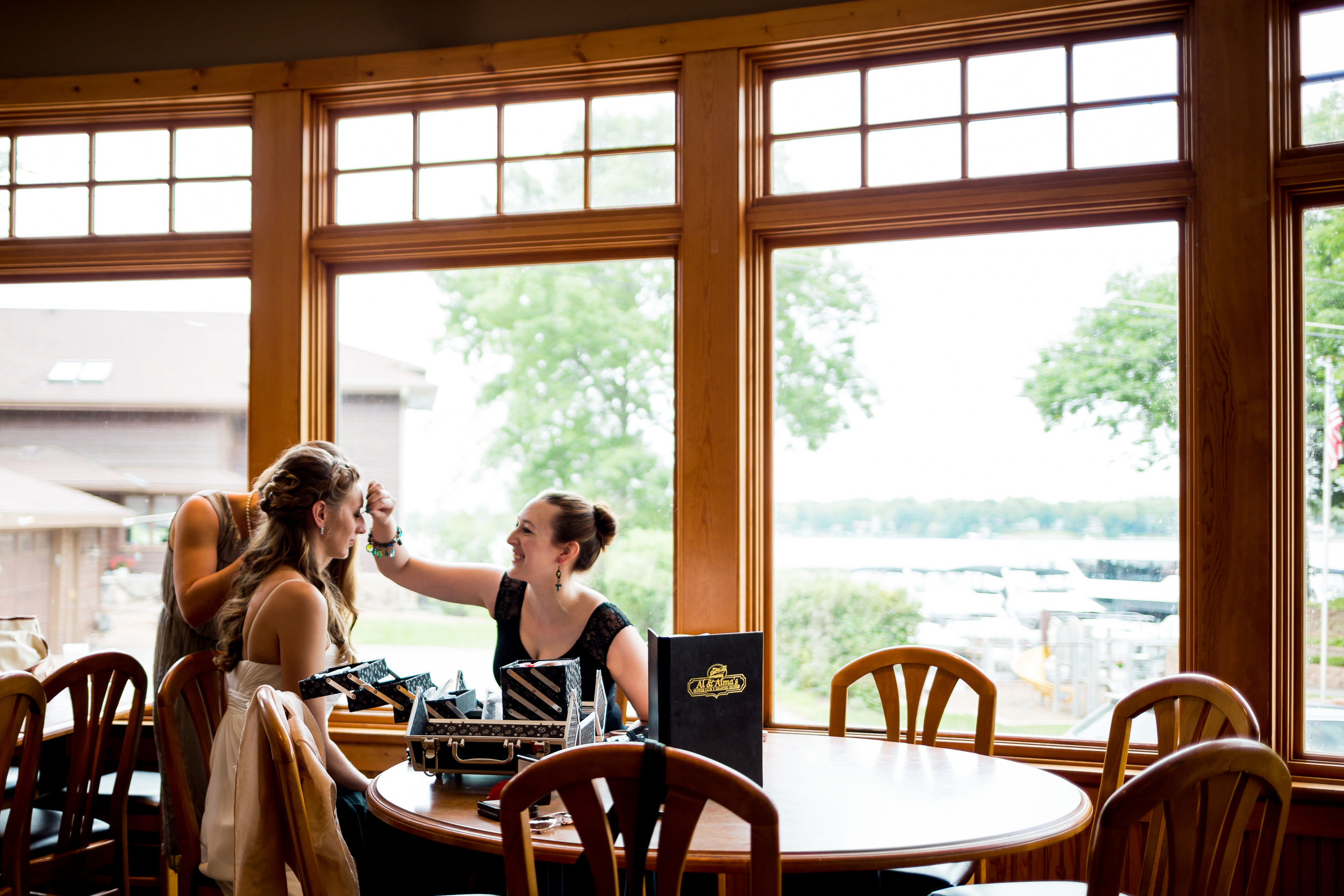 Our bride Robin sits near the window light as her sister Josie does her makeup.
