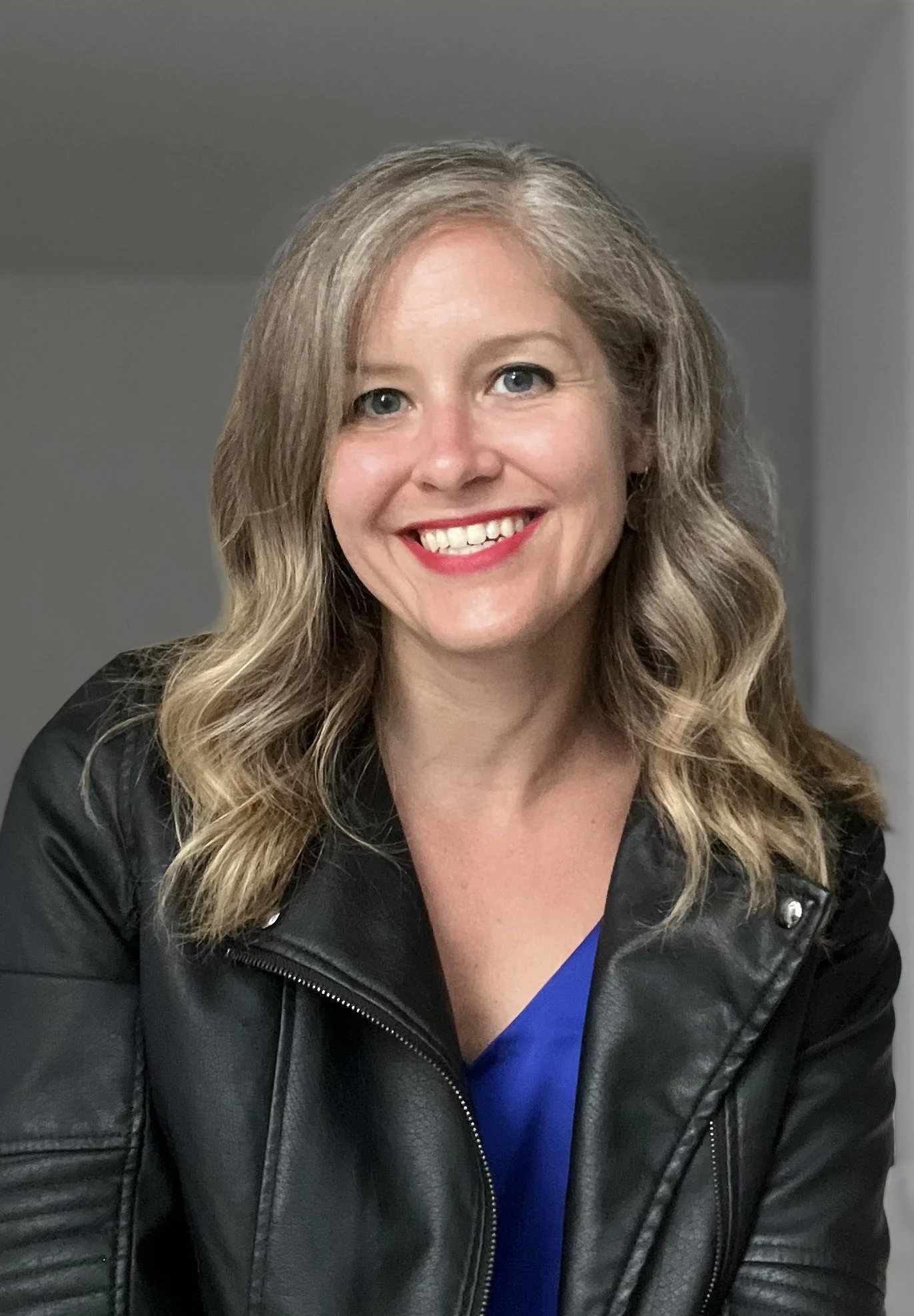 Headshot wearing black leather jacket and cobalt blue top