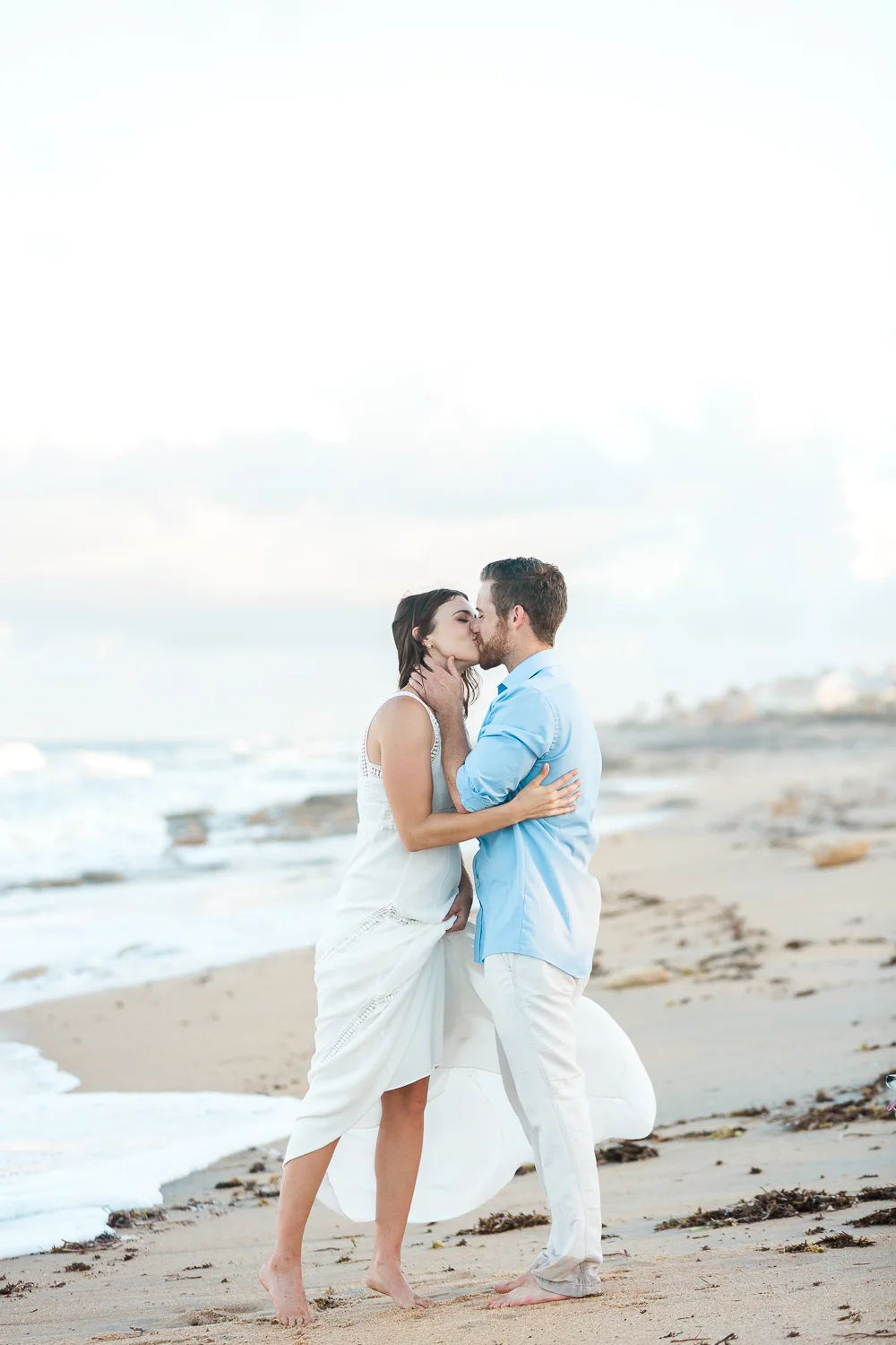 engaged couple kissing at the beach