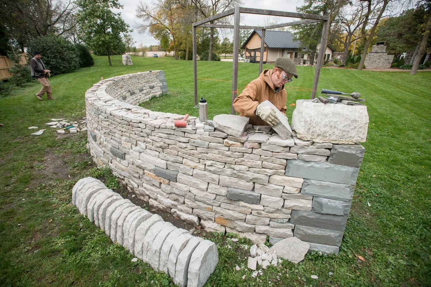Daniel Peterson of HabAdapt Landscape Design places a coping stone on an arched, drystone wall that serves as a grounding structure to "The Cube" pergola ceremony site at The Gardens of Castle Rock.
