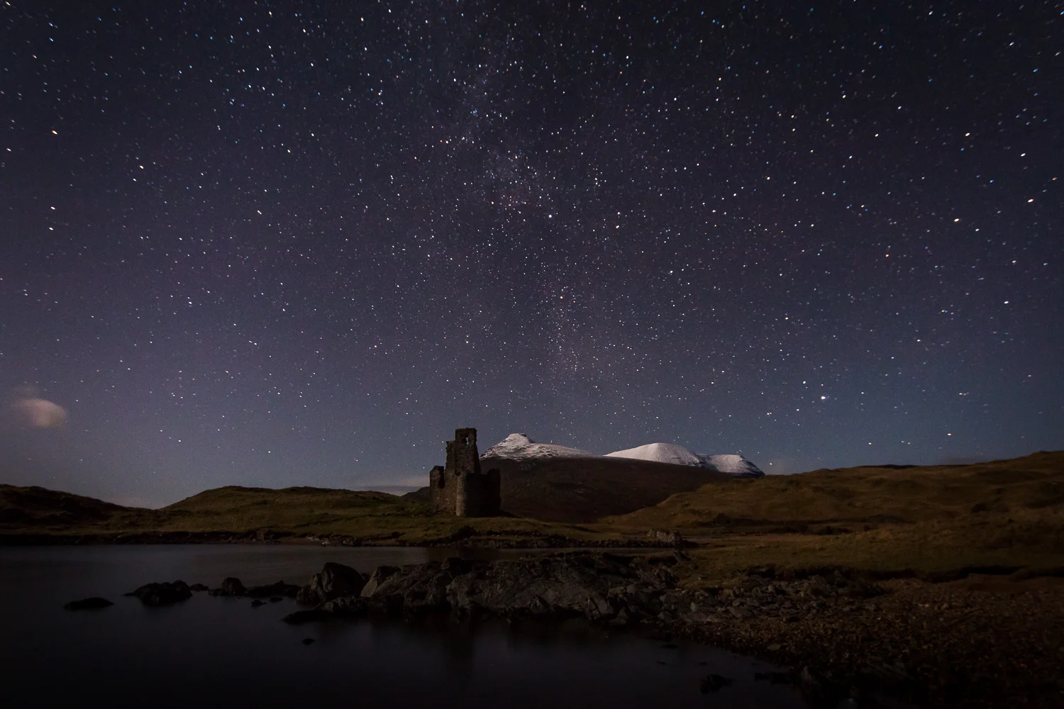 Ardvreck Castle under the Stars with a snow capped Quinag in the background.