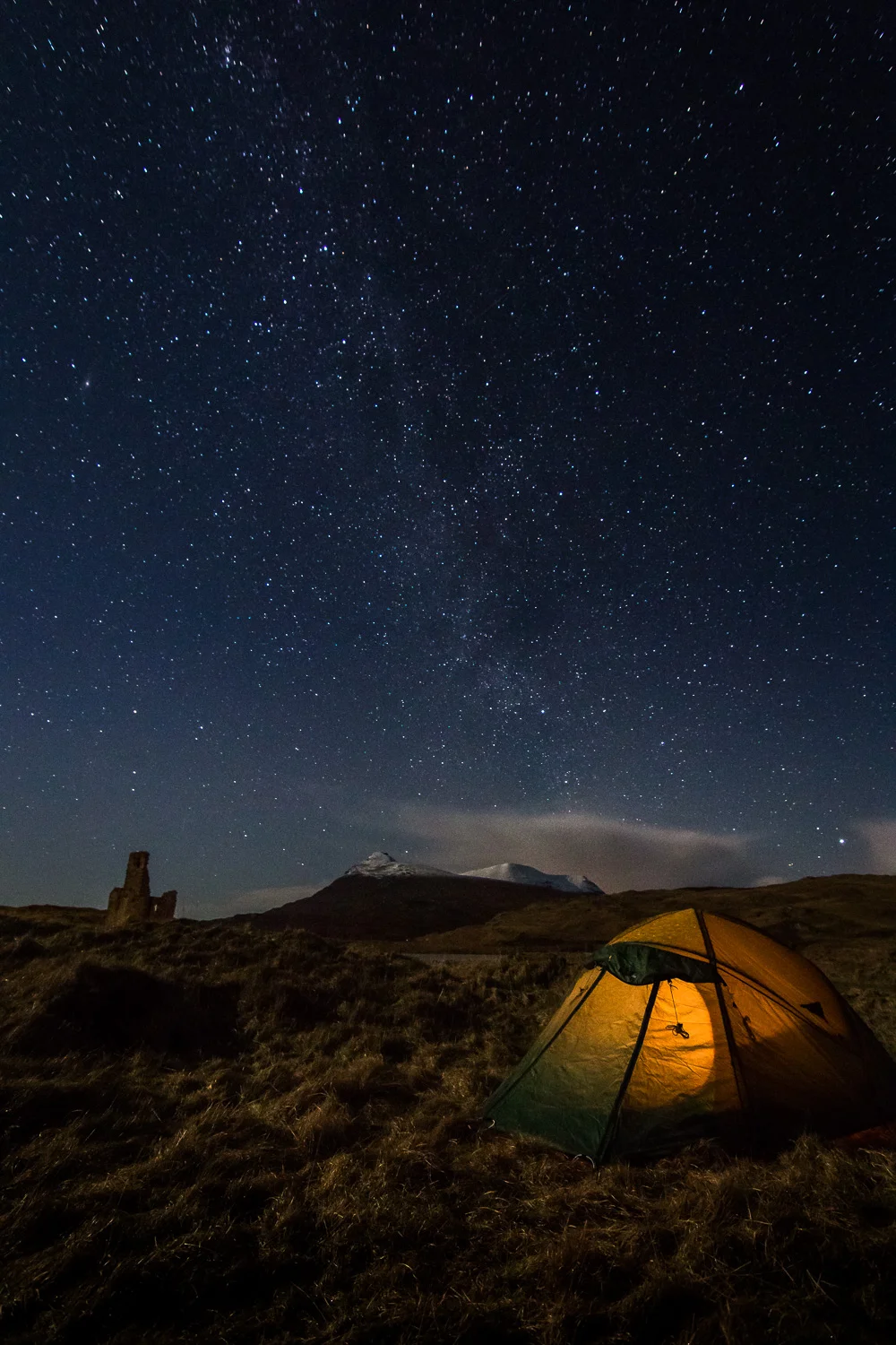 Camp and Ardvreck Castle with the faint tail of the Milky Way overhead.