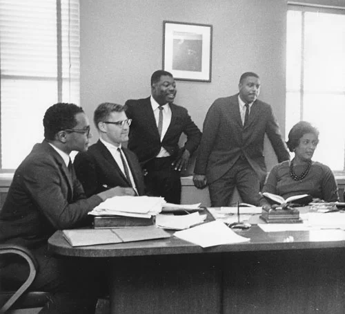 Five LDF lawyers behind Thurgood Marshall's desk in 1962 (from left, clockwise) Derrick Bell, Frank Heffron, Norman Amaker, Leroy Clark, Constance Baker Motley. (Courtesy NAACP Legal Defense and Education Fund, Inc.)