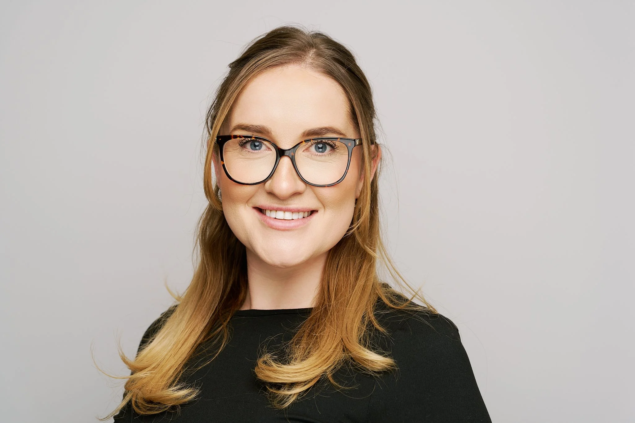 Studio-quality corporate headshot taken on location with a clean light grey background for company profiles