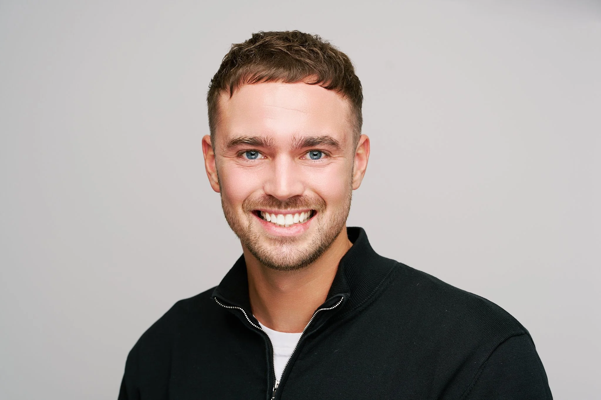 Relaxed professional headshot created on location with studio lighting against a neutral light grey background