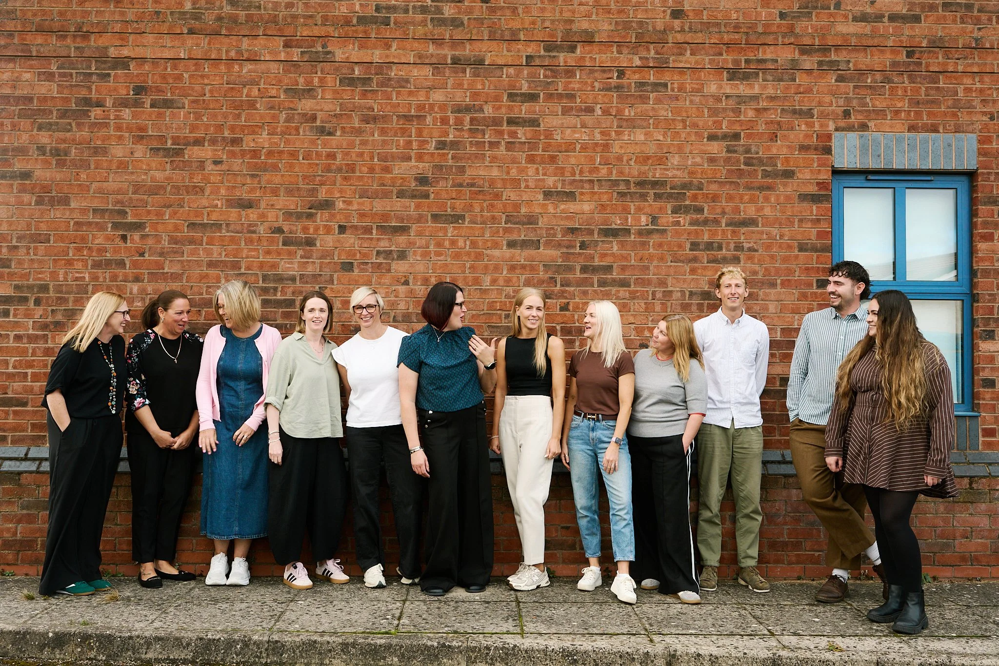 The Bodie Hodges team chatting together beside a wall during their staff photoshoot.