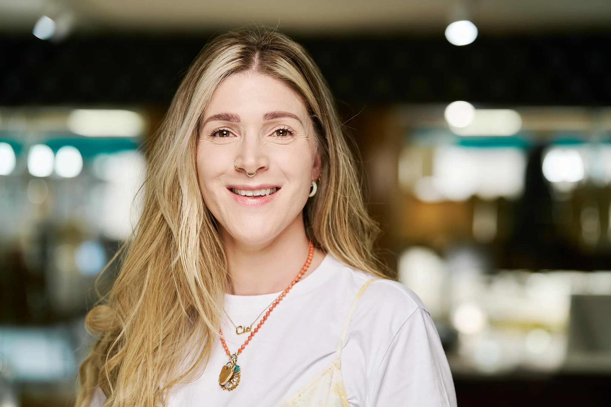 Professional headshot of jewellery consultant inside Northampton jewellery shop with display cabinets in the background.