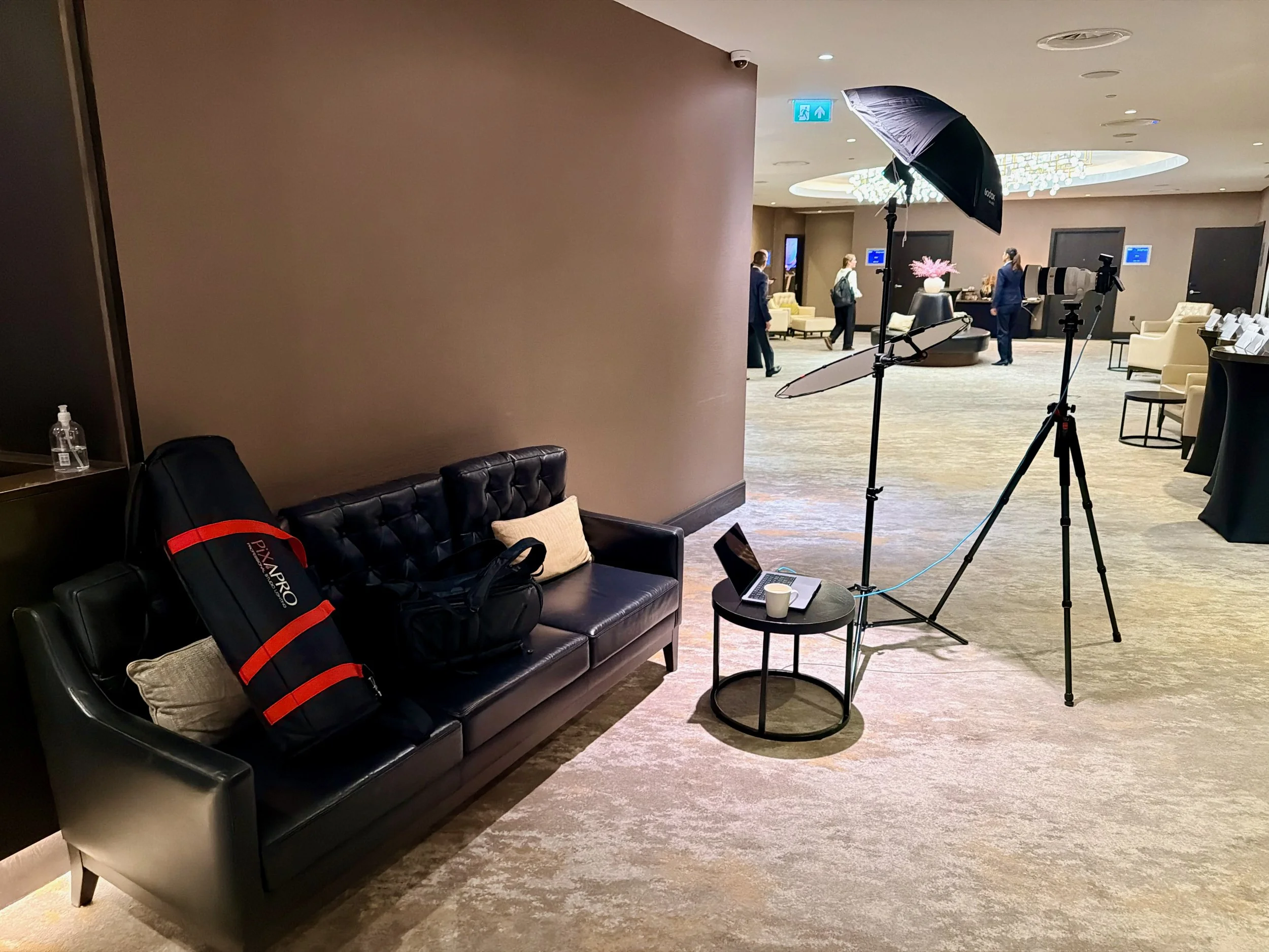 On-location headshot setup for BESA at Hilton London Bankside, with a softbox, reflector, tripod-mounted camera and laptop.