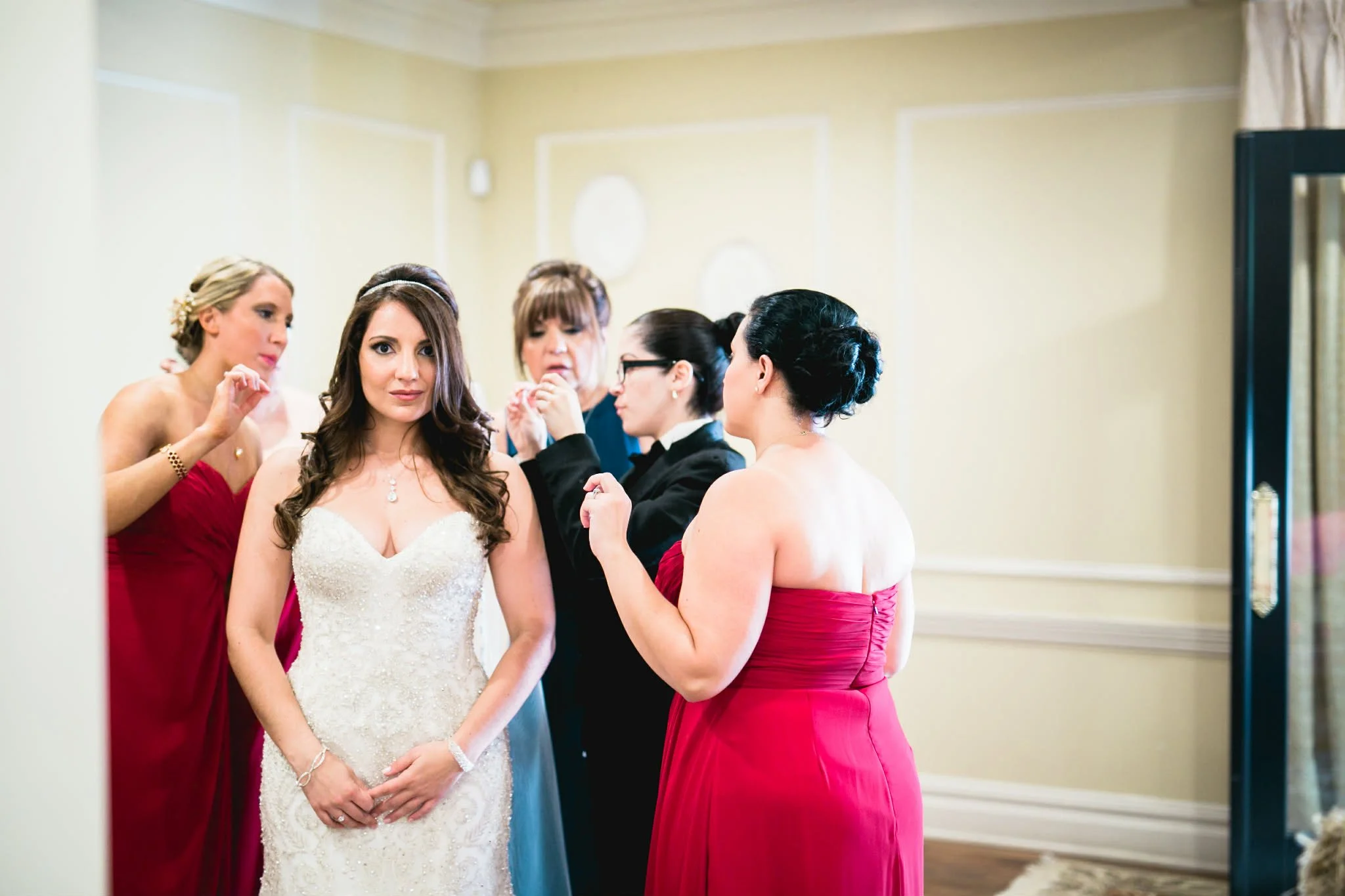 Group of women preparing a bride with makeup and hair in a dressing room.