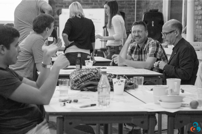 Several small groups engaged in animated discussion during the brainstorming phase of the World Usability Day UX workshop, each developing ideas in parallel. Anna Newman, photographer.