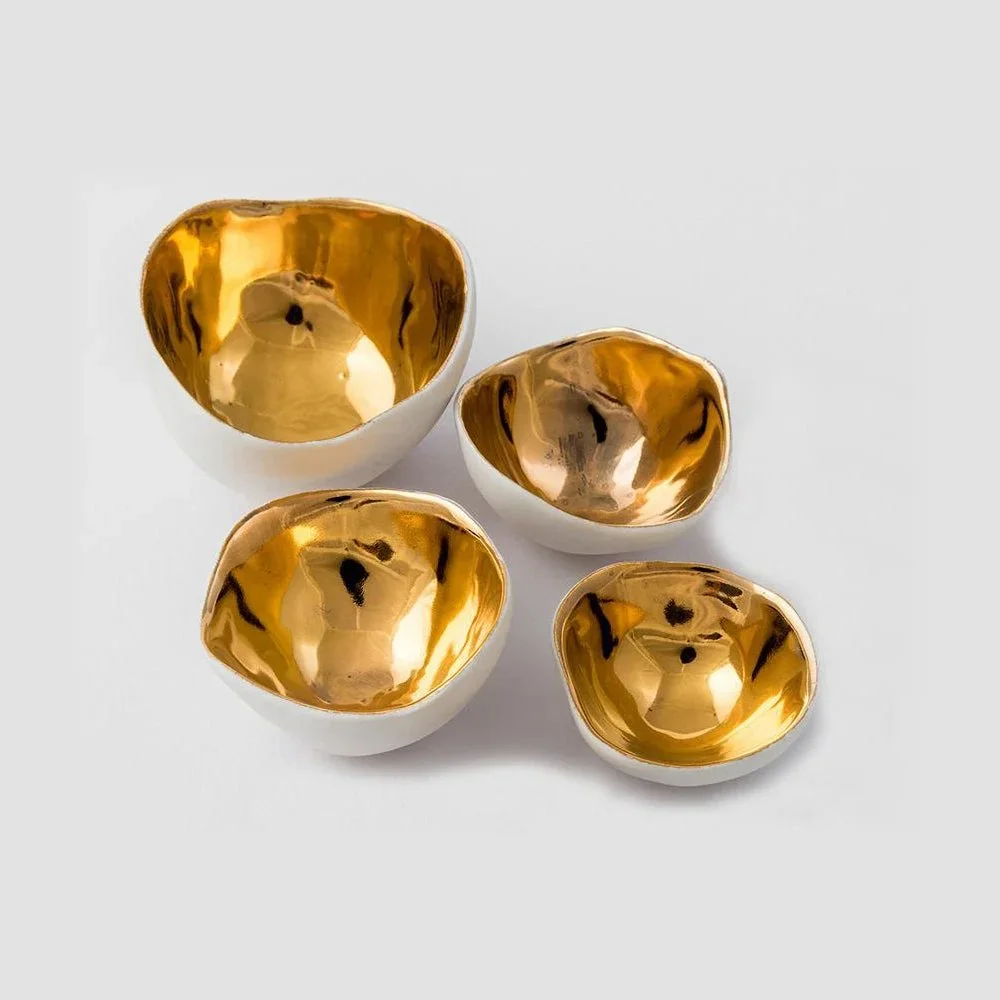 A group of tiny white porcelain bowls by Penny Little lined with gold lustre