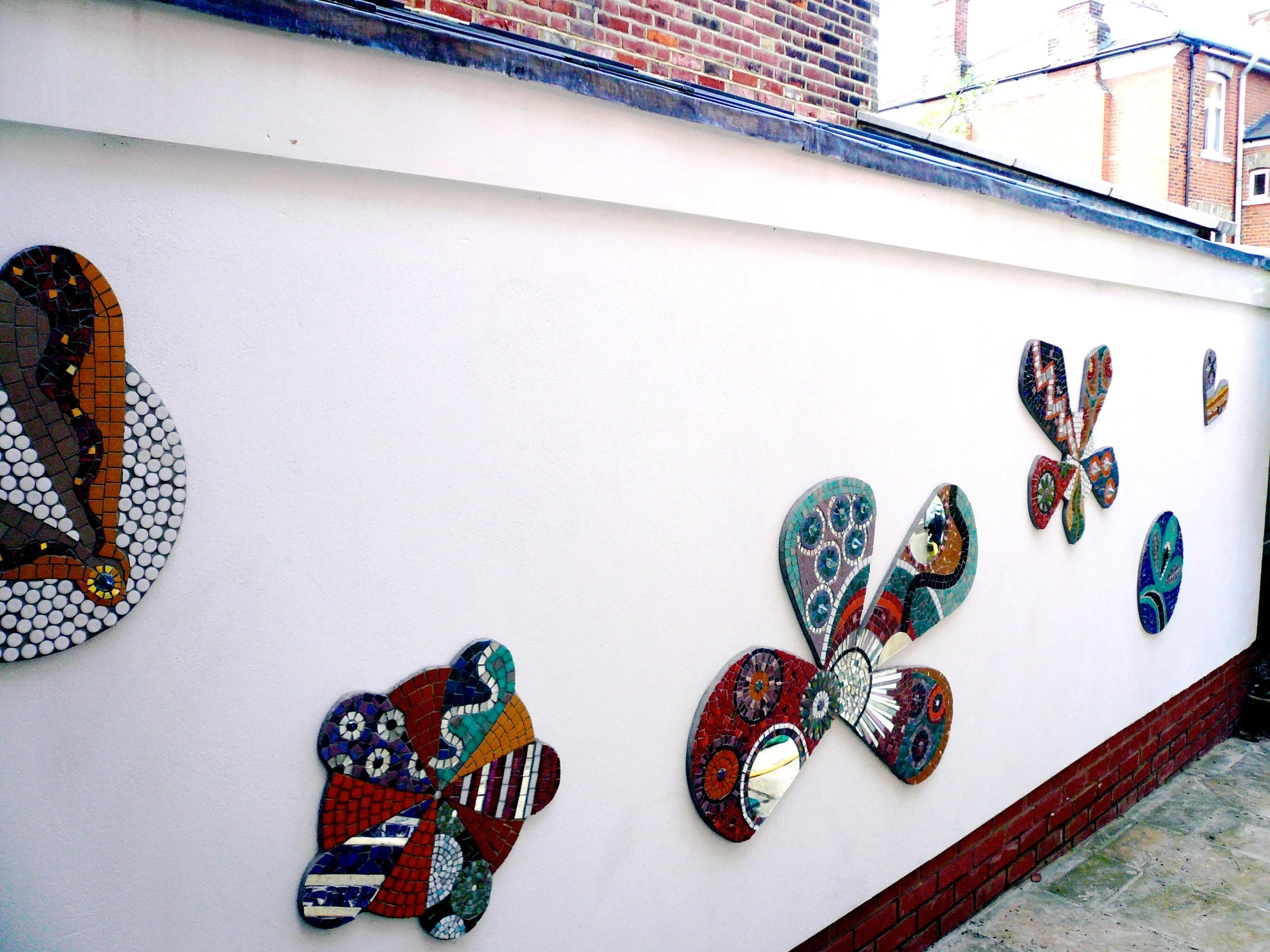 Here is the full view, stunning work, based on simple patterns but using a wide pallet of mosaic materials. Liz & Sharon worked on this together overa month period. Made on plywood by gluing the tiles. Grouted and then screwed to the wall. Liz is a dab handwith the jigsaw cutting those shapes!