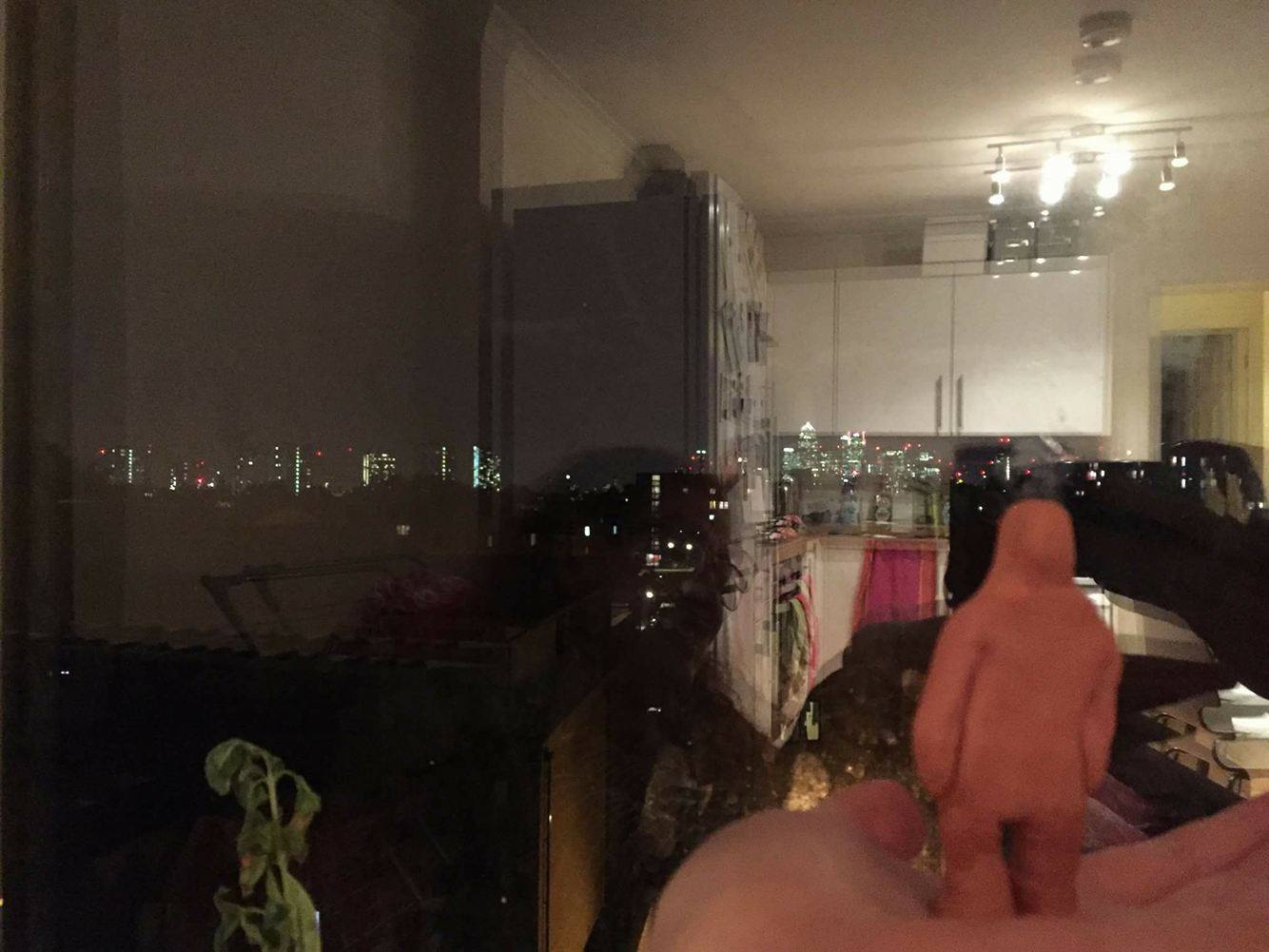 Place 1: GOOD Living room staring out the window at the lights (in the dark) feeling content and happy and lucky to live in london, safe high up looking over. Listening to music in the dark. Shape and Colour: Warm, Dark, Safe, Orange, Yellow, Round, Whole.