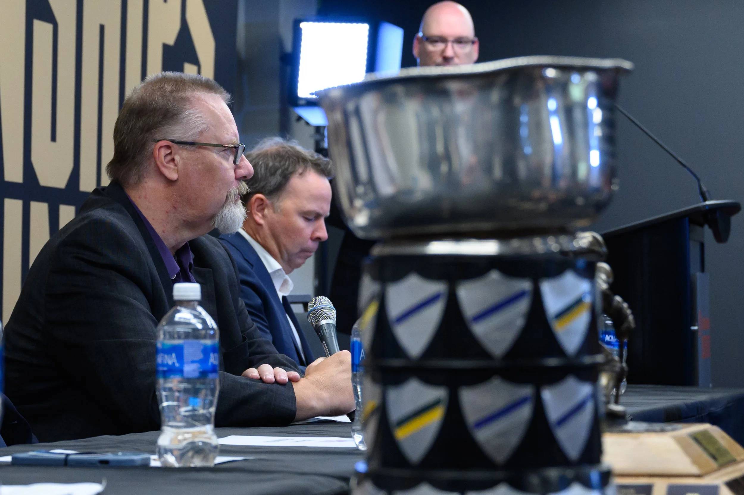 Scott Gray sits at media table while the U Cup trophy sits in the foreground