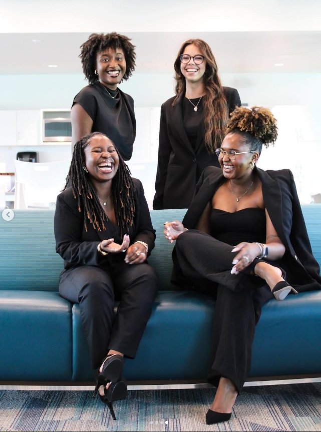 Four female students laugh while posing together