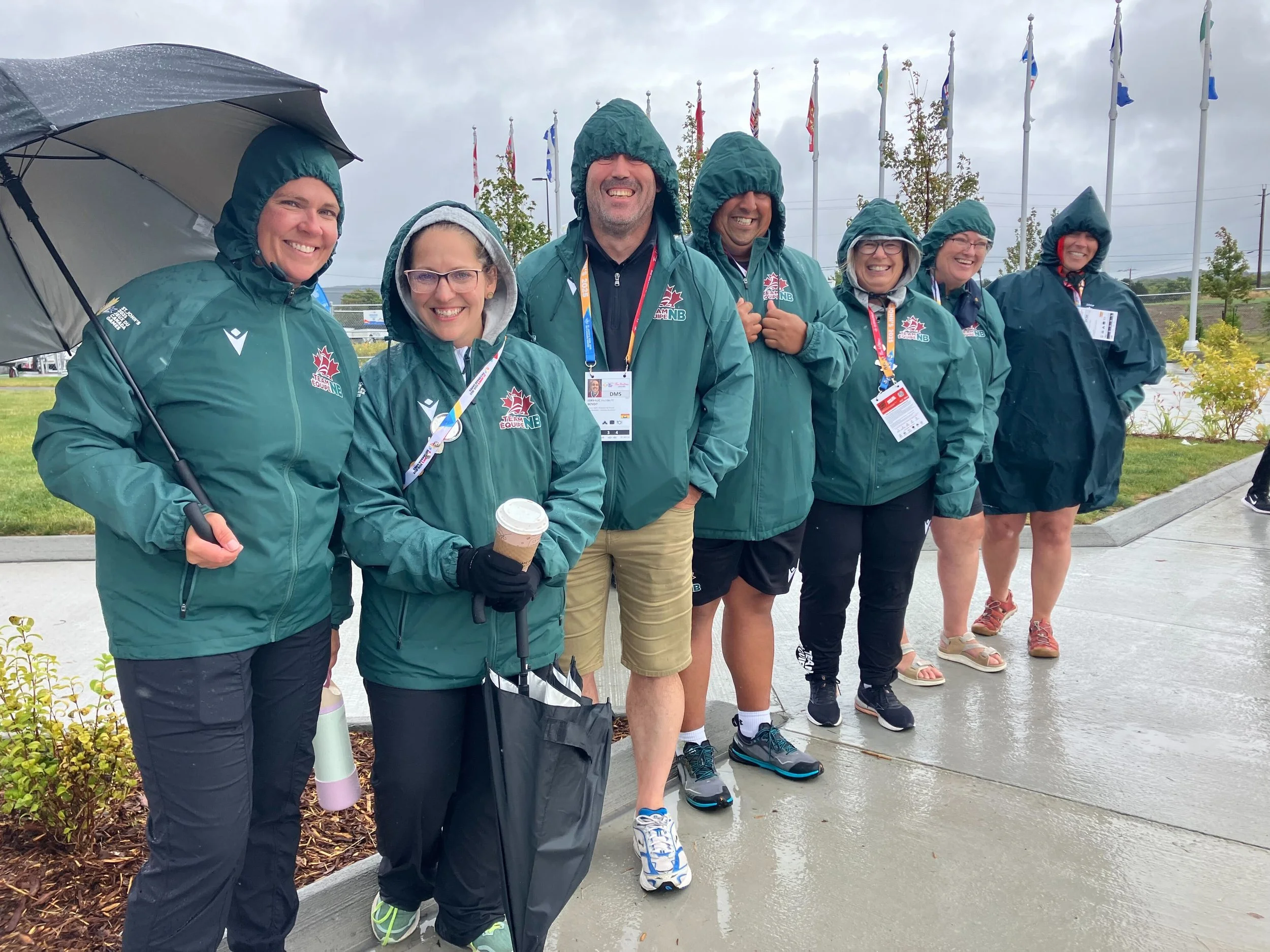 A group of volunteers in rain jackets with umbrellas