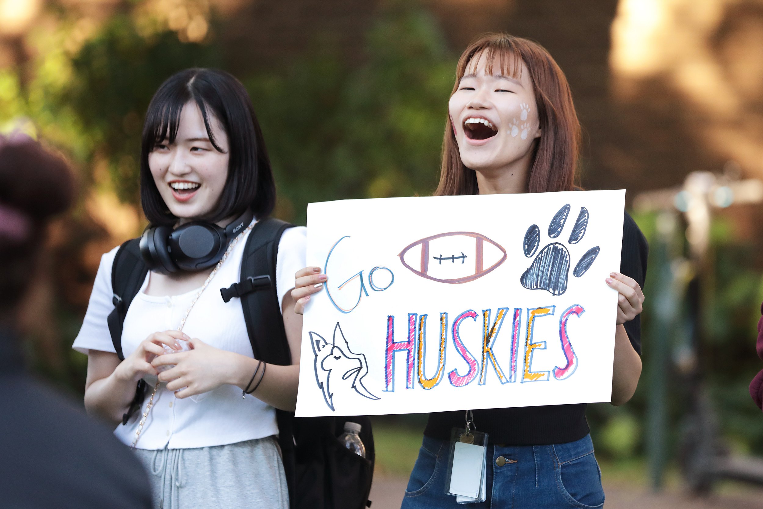 Two fans cheering on the huskies with a sign