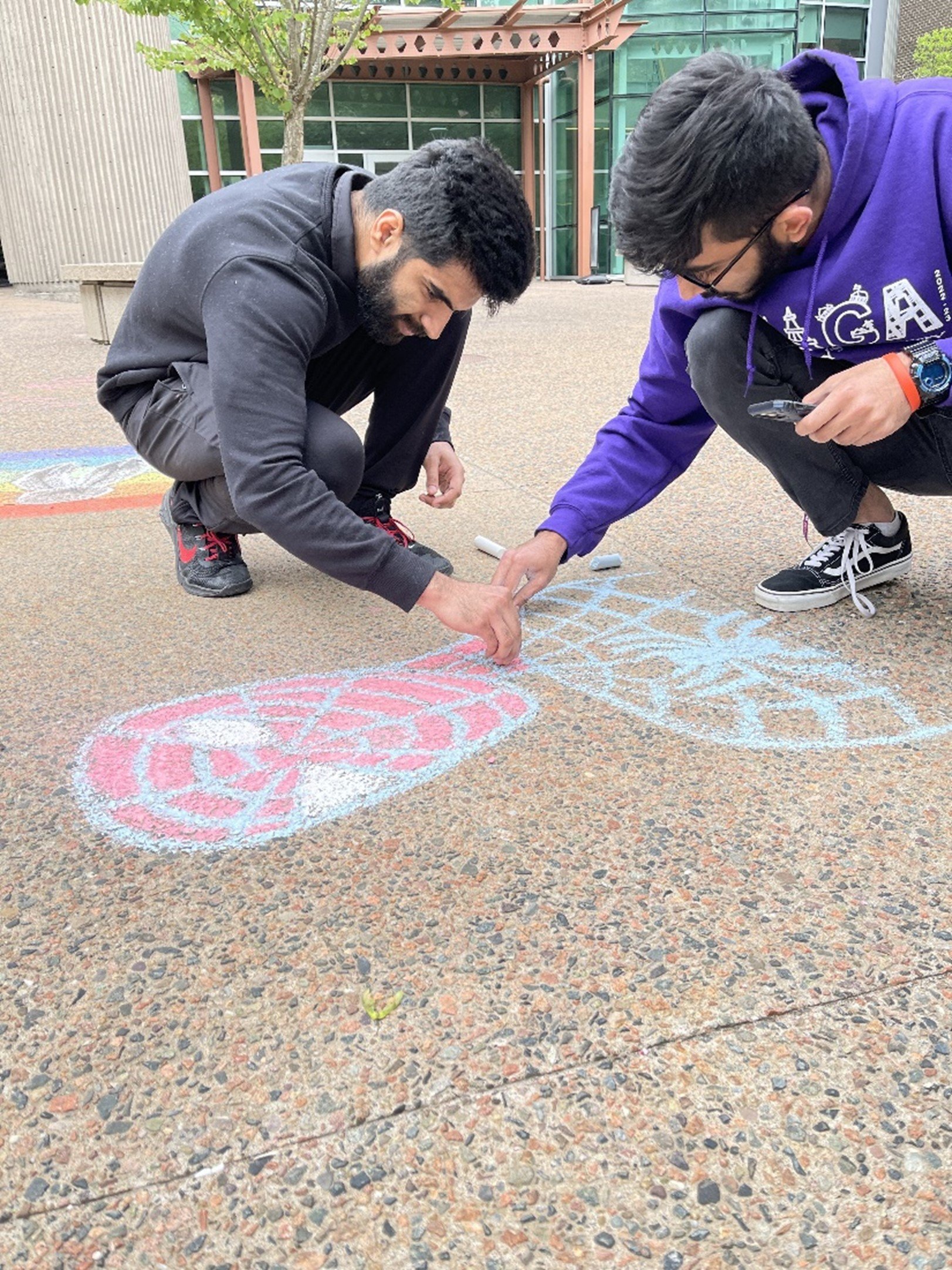  Two students draw a Spiderman image in chalk. 