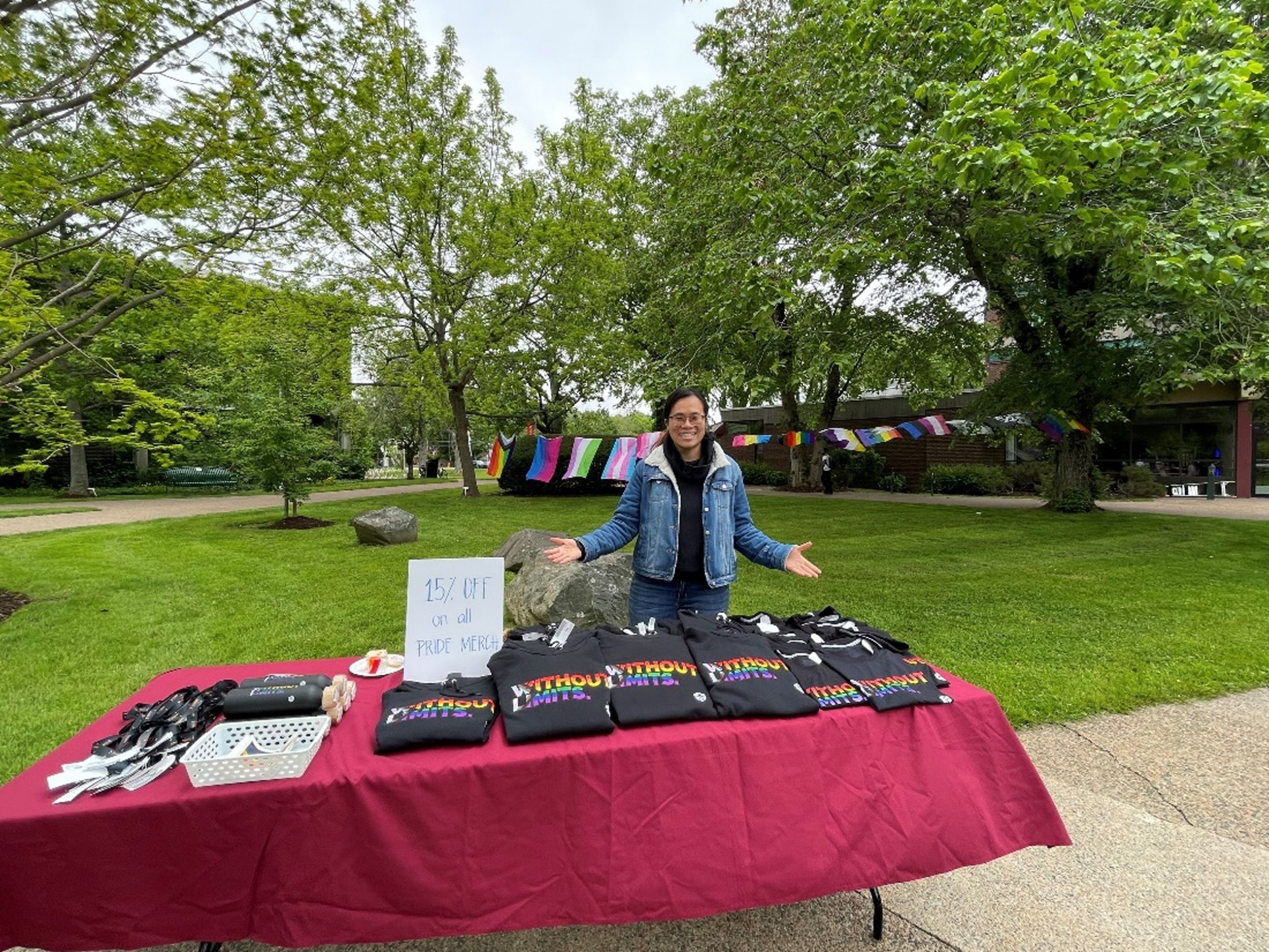  Bookstore staff member stands in front of Pride apparel table. 