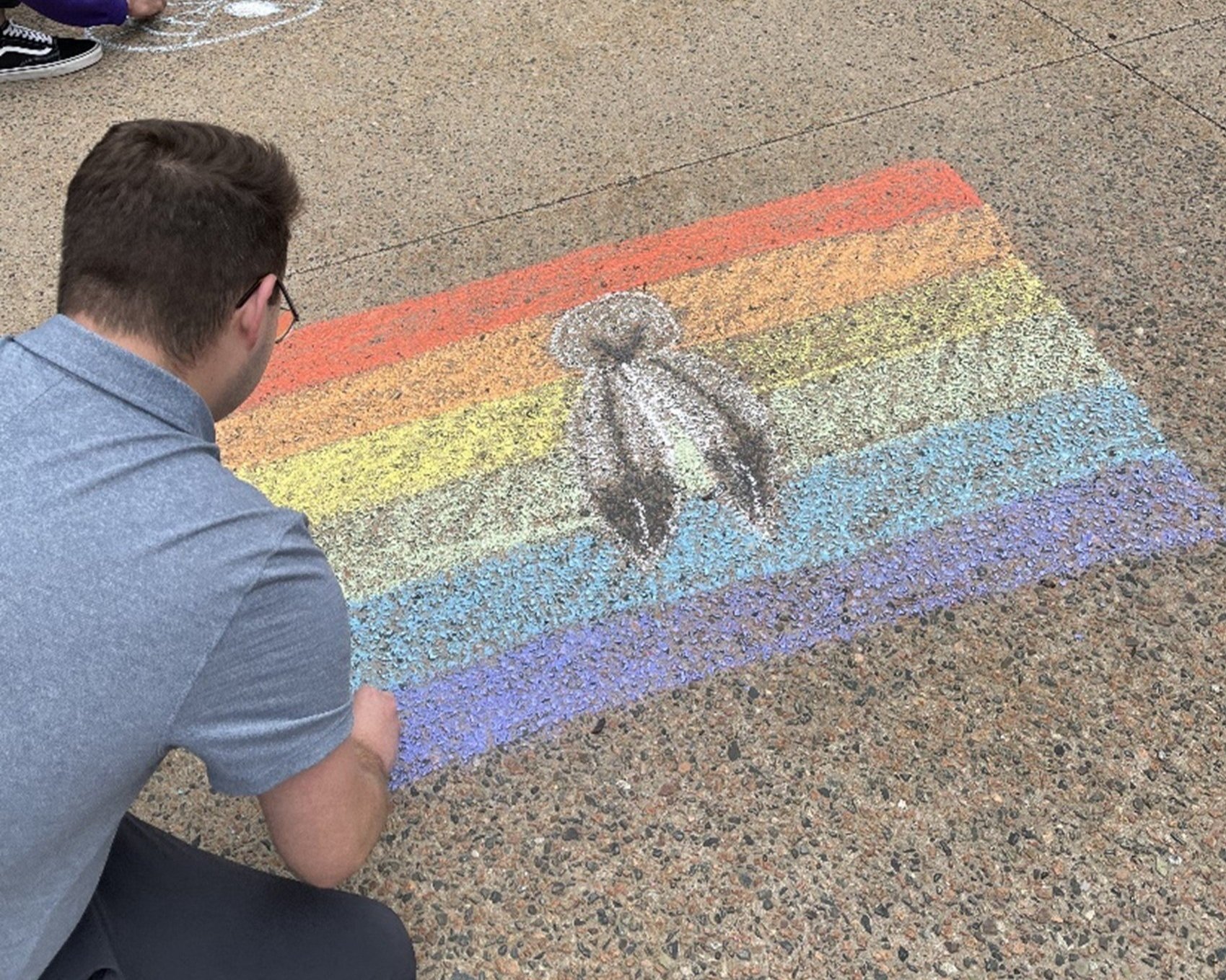  Kyle Cook, Indigenous Student Advisor, drawing two-spirit pride flag in chalk.  