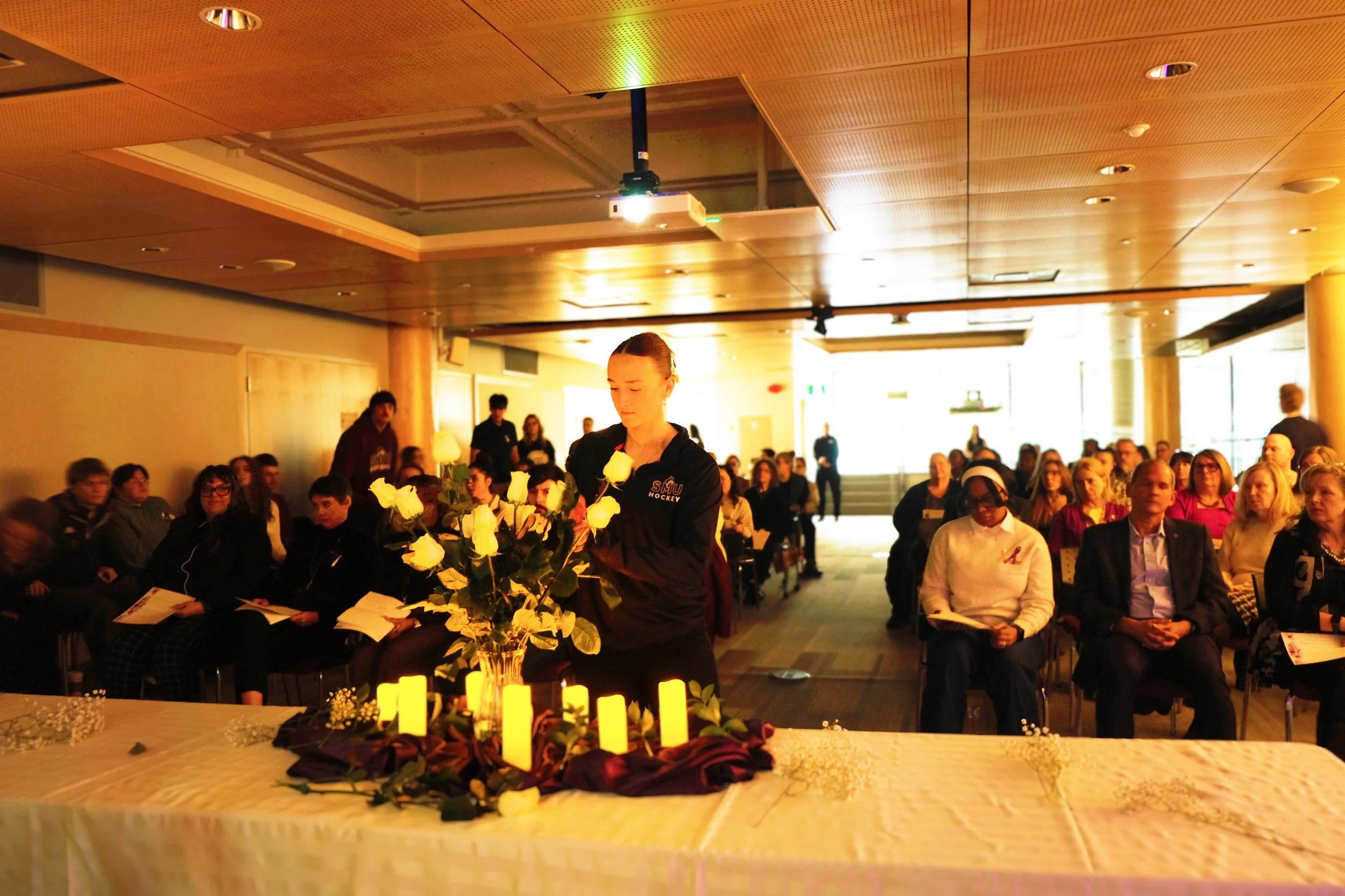  A student places a rose during the National Day of Remembrance and Action on Violence Against Women ceremony 