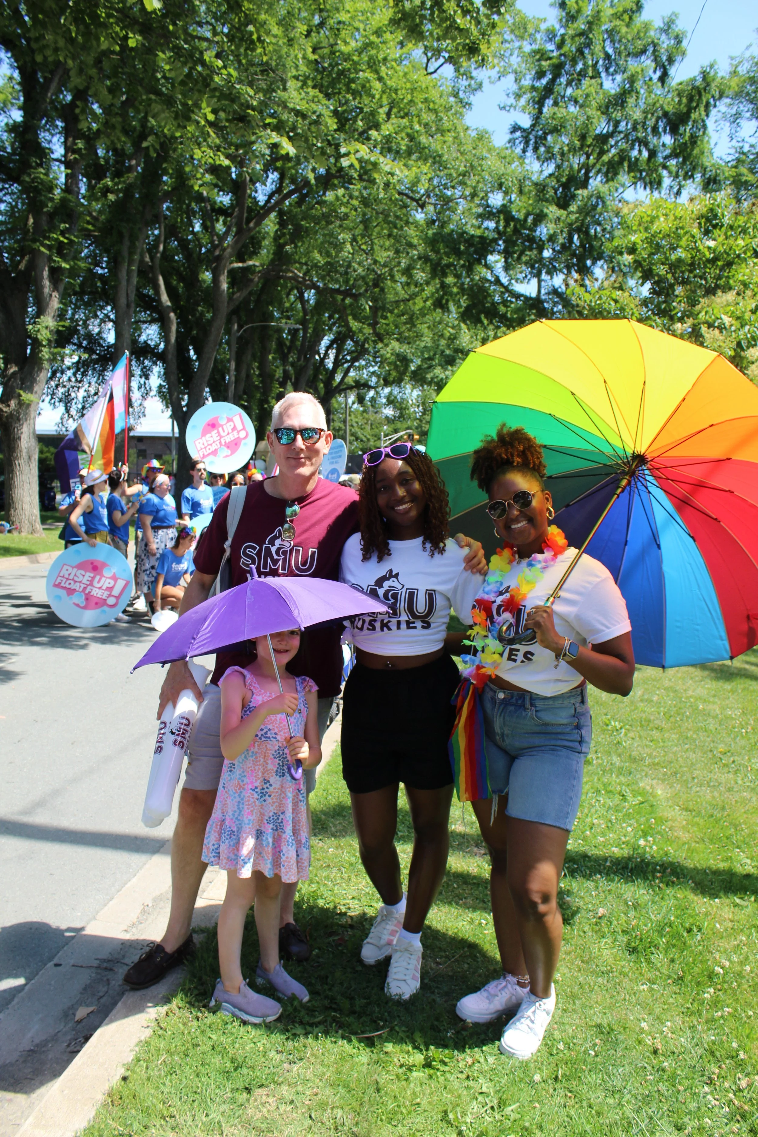 Four people in rainbow and Huskies gear at the pride parade