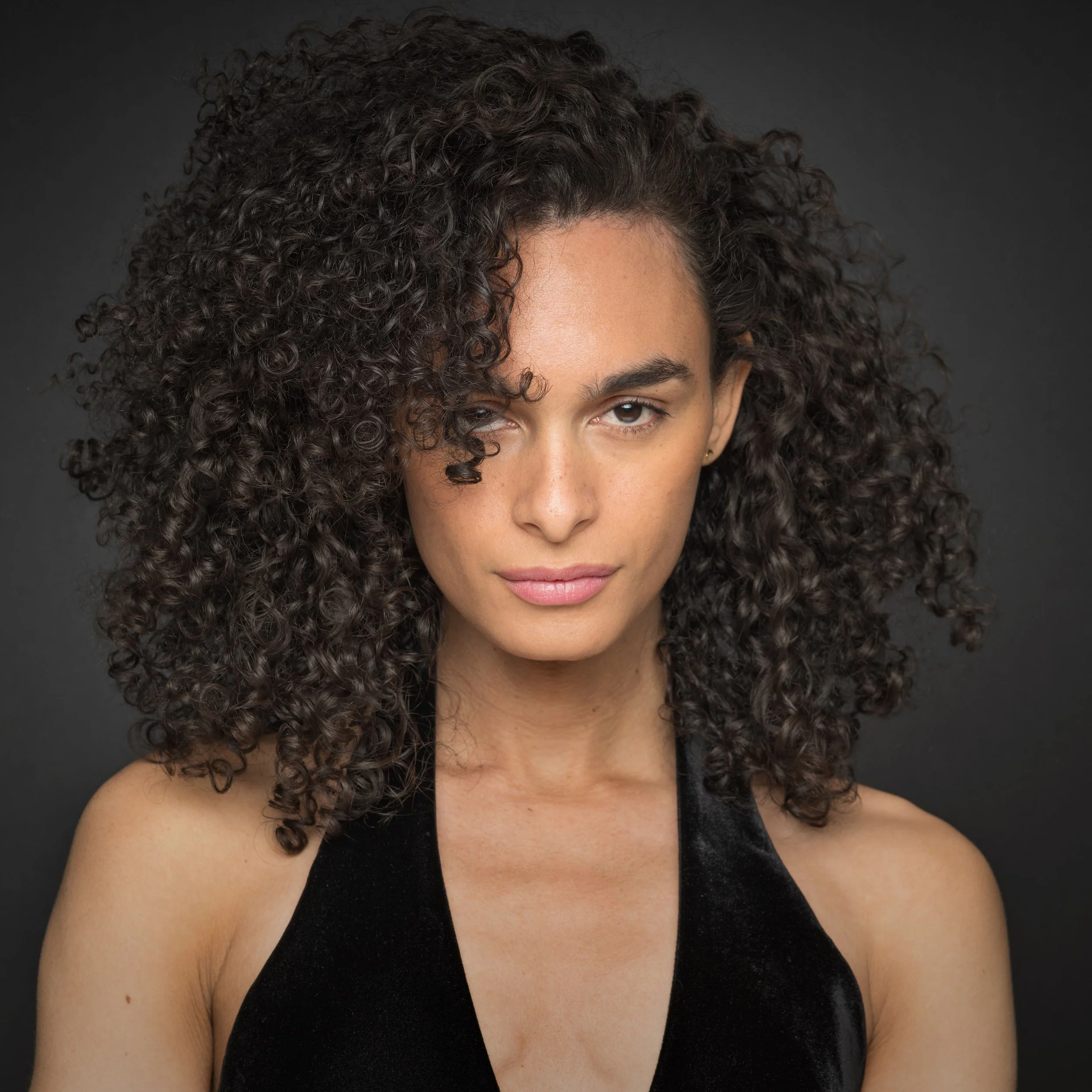 Chrissy is a Black woman with shoulder length curly brown hair. She looks directly into the camera.