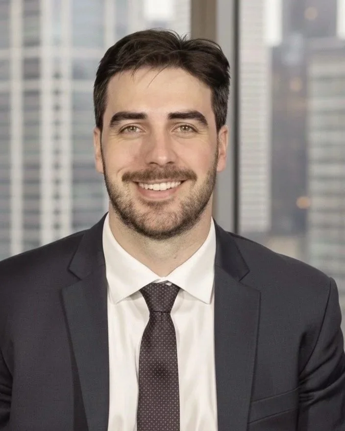 Peter is a white man with short dark hair and a beard. He wears a business suit.