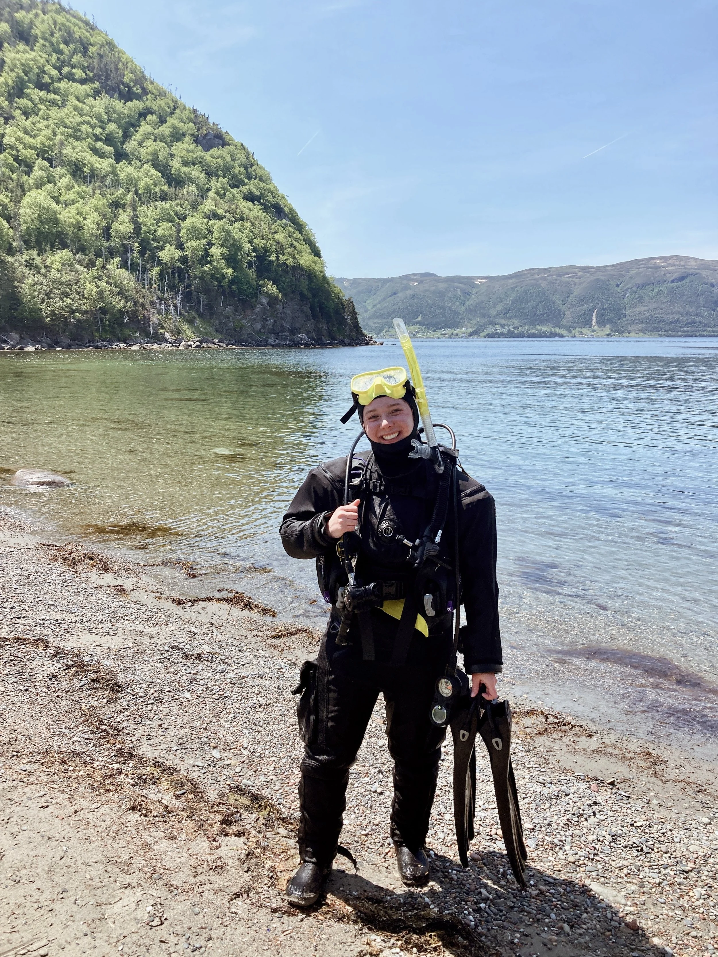 Jill poses in full diving gear on a shoreline