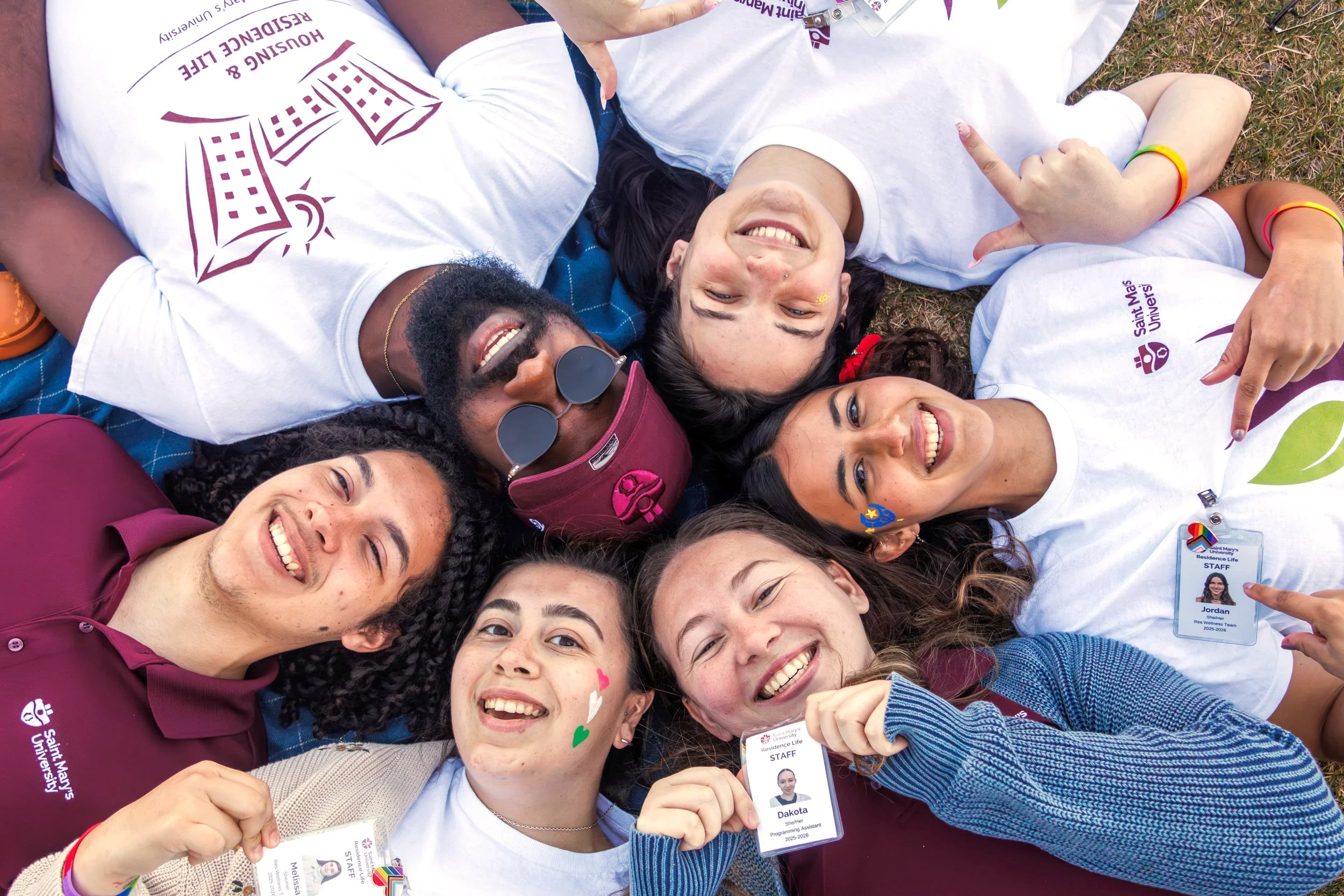 A group of people lay in a circle and smile up at the camera