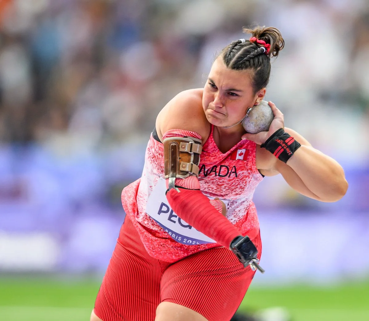 Katie throws shot put while wearing a red Canada jersey