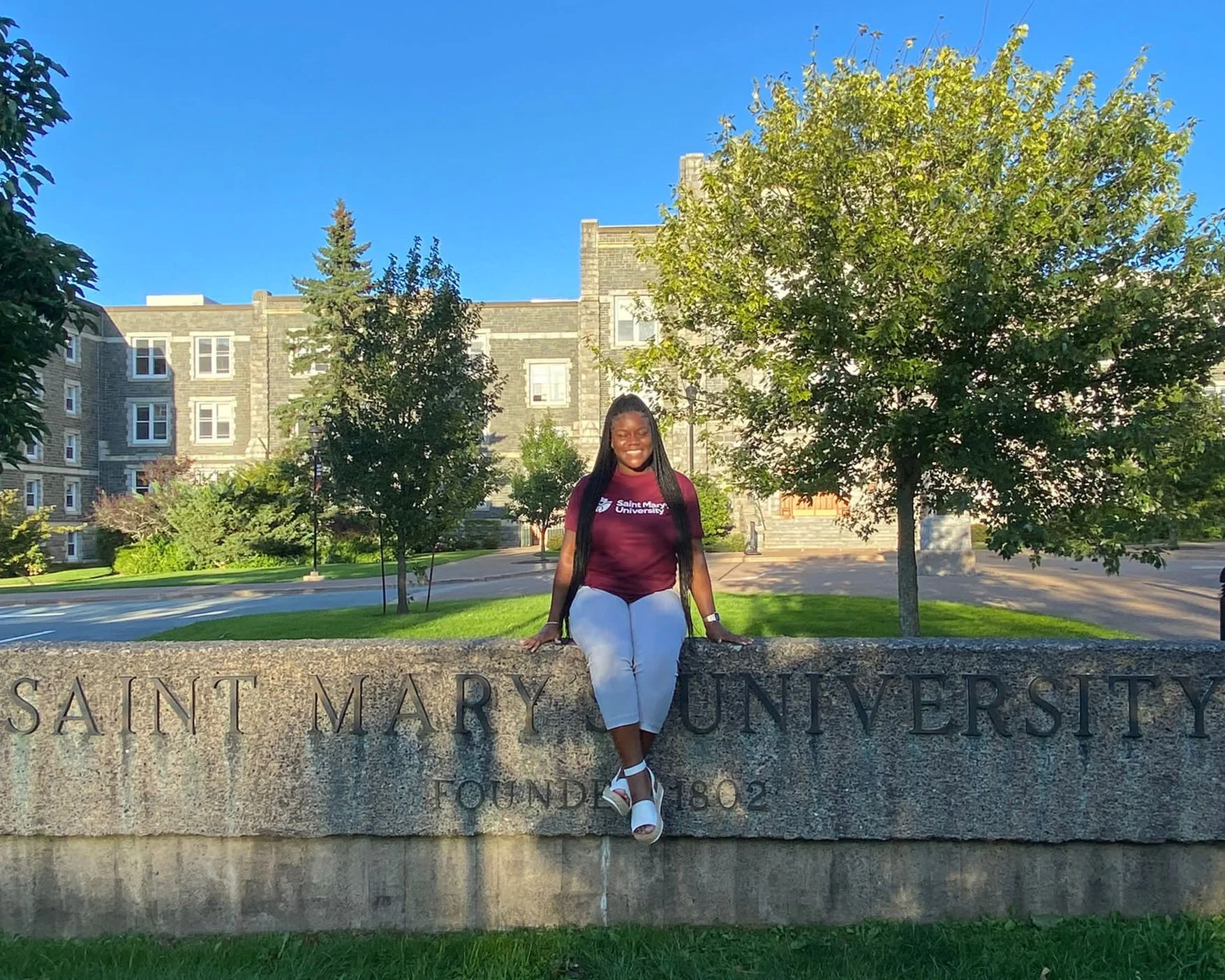 Tashauna sits on the concrete SMU sign in front of McNally